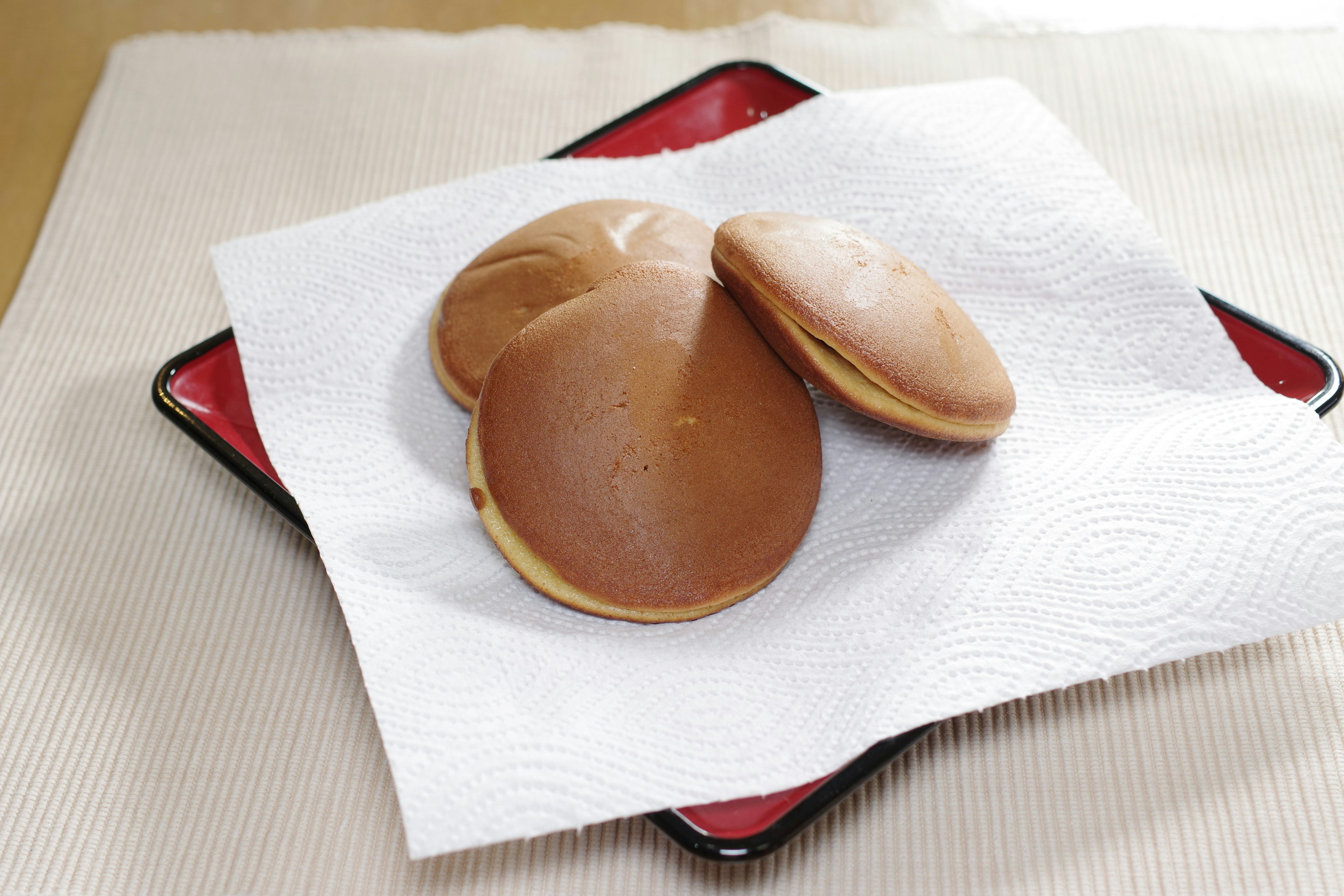 Trois dorayaki sur un papier blanc dans une assiette noire