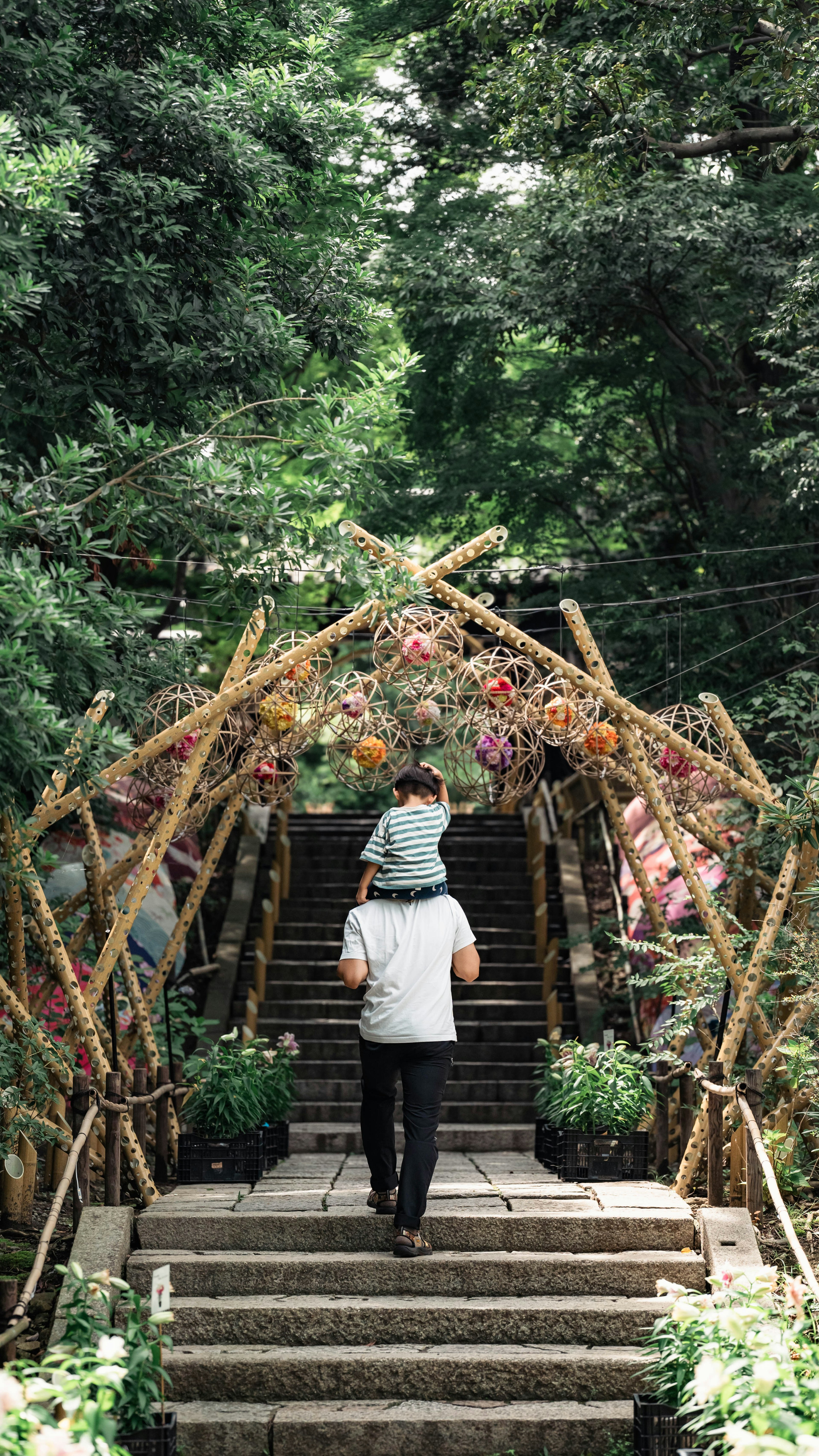 A father carrying a child on his back walking up stairs in a lush green environment