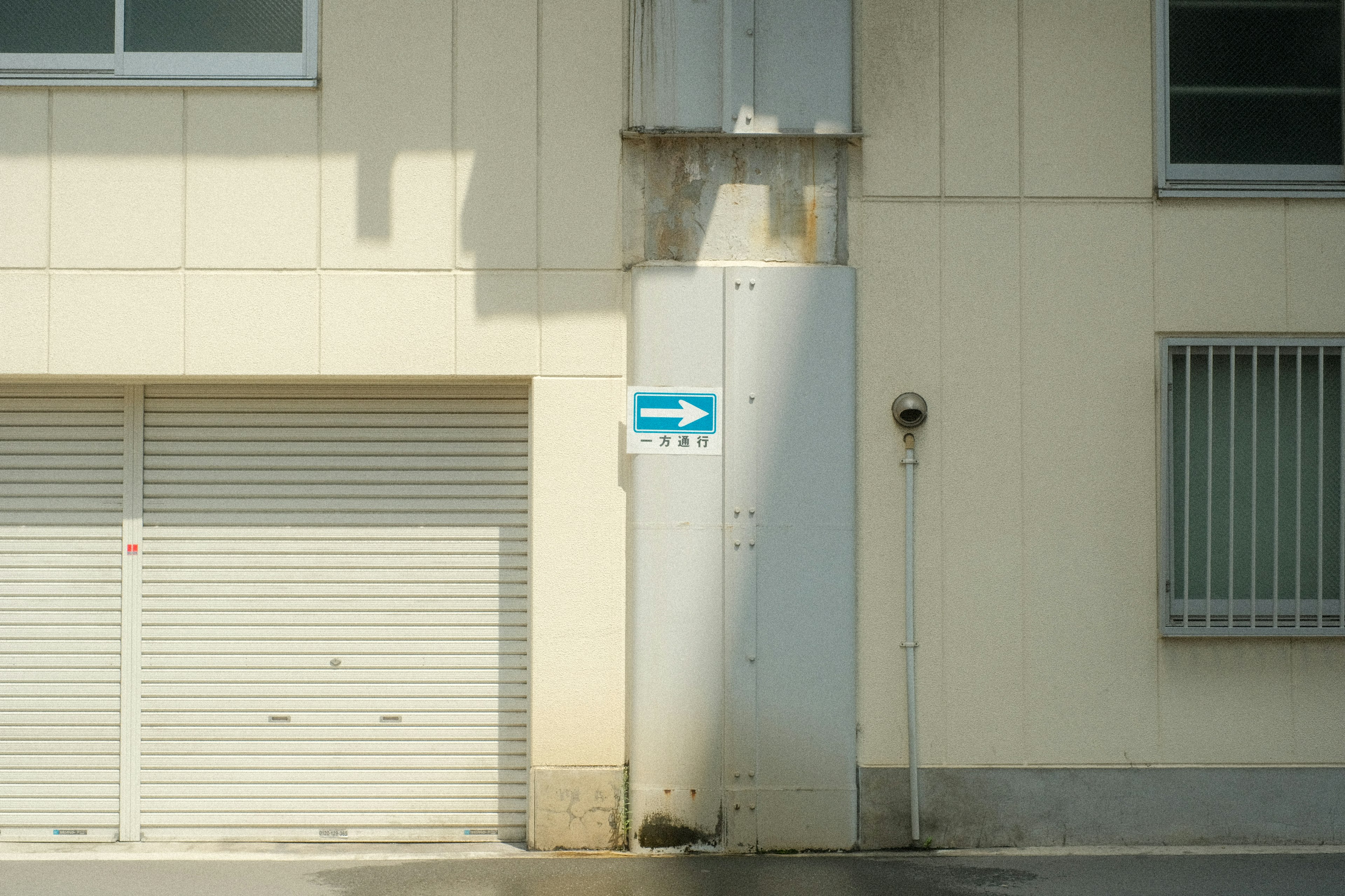 Blaues Pfeilschild an einer Gebäudewand mit Rolltor