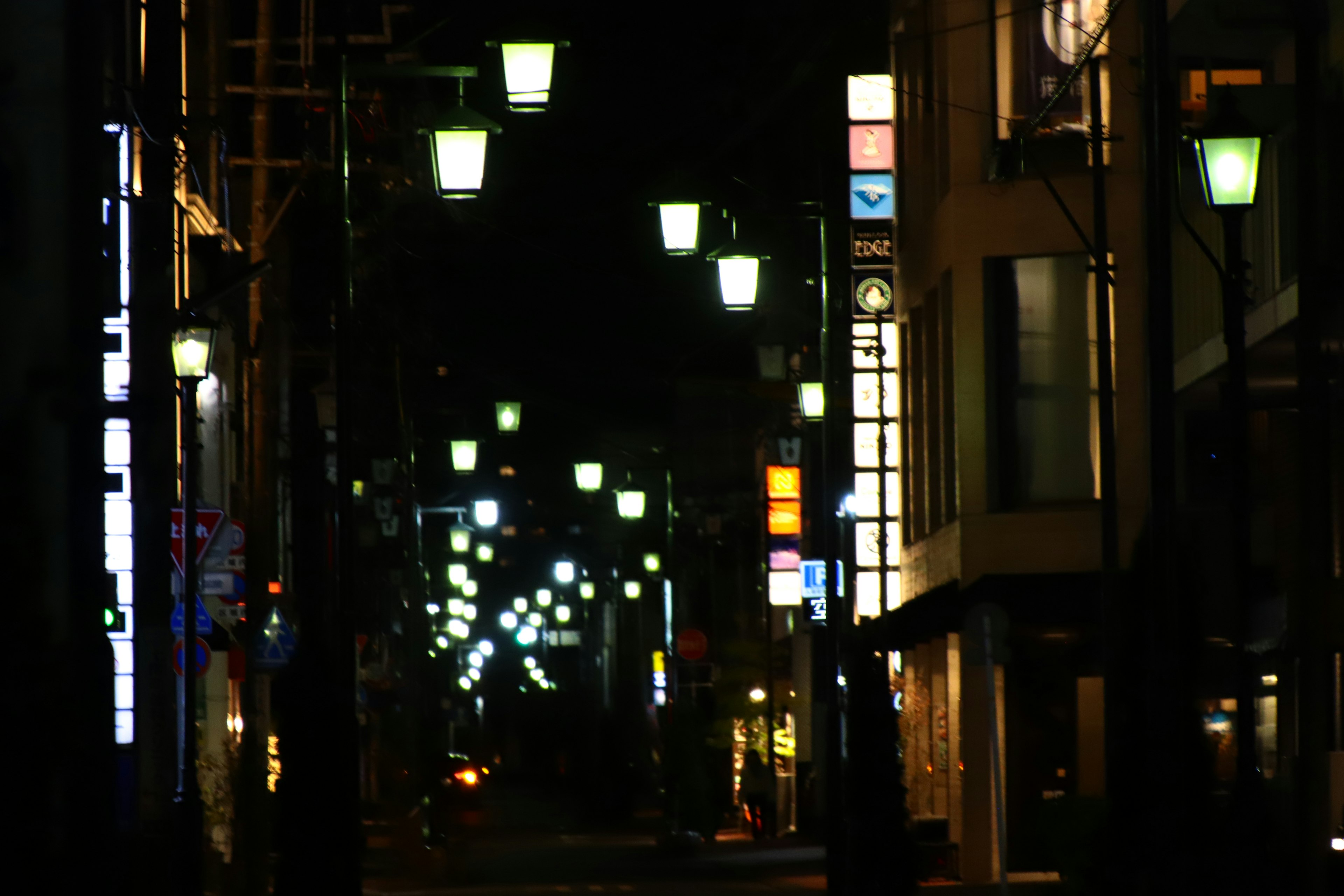 Escena nocturna de una calle con luces y edificios llamativos