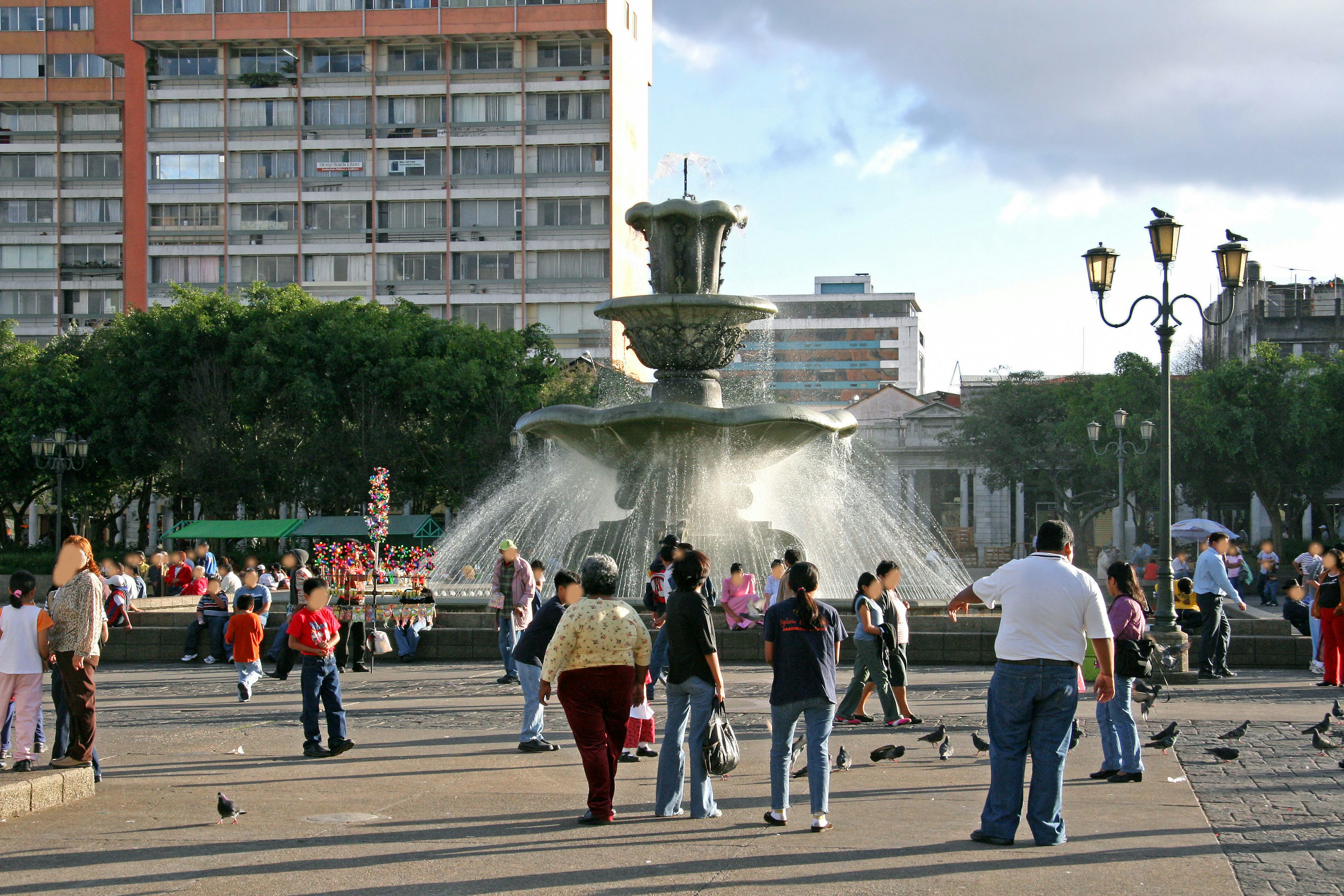 Fontaine au centre d'une place avec des gens rassemblés