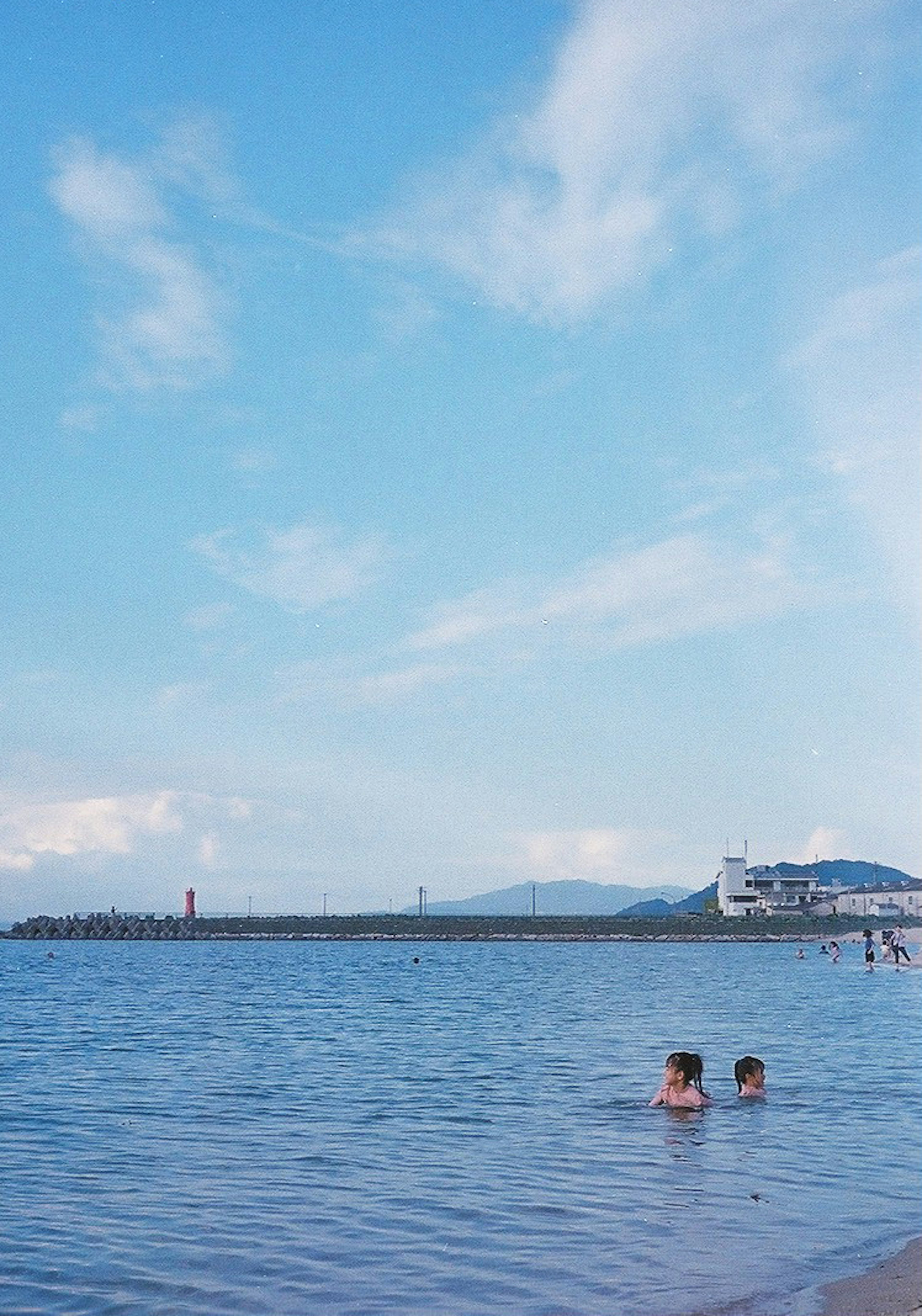 Dos niños jugando en agua tranquila bajo un cielo azul