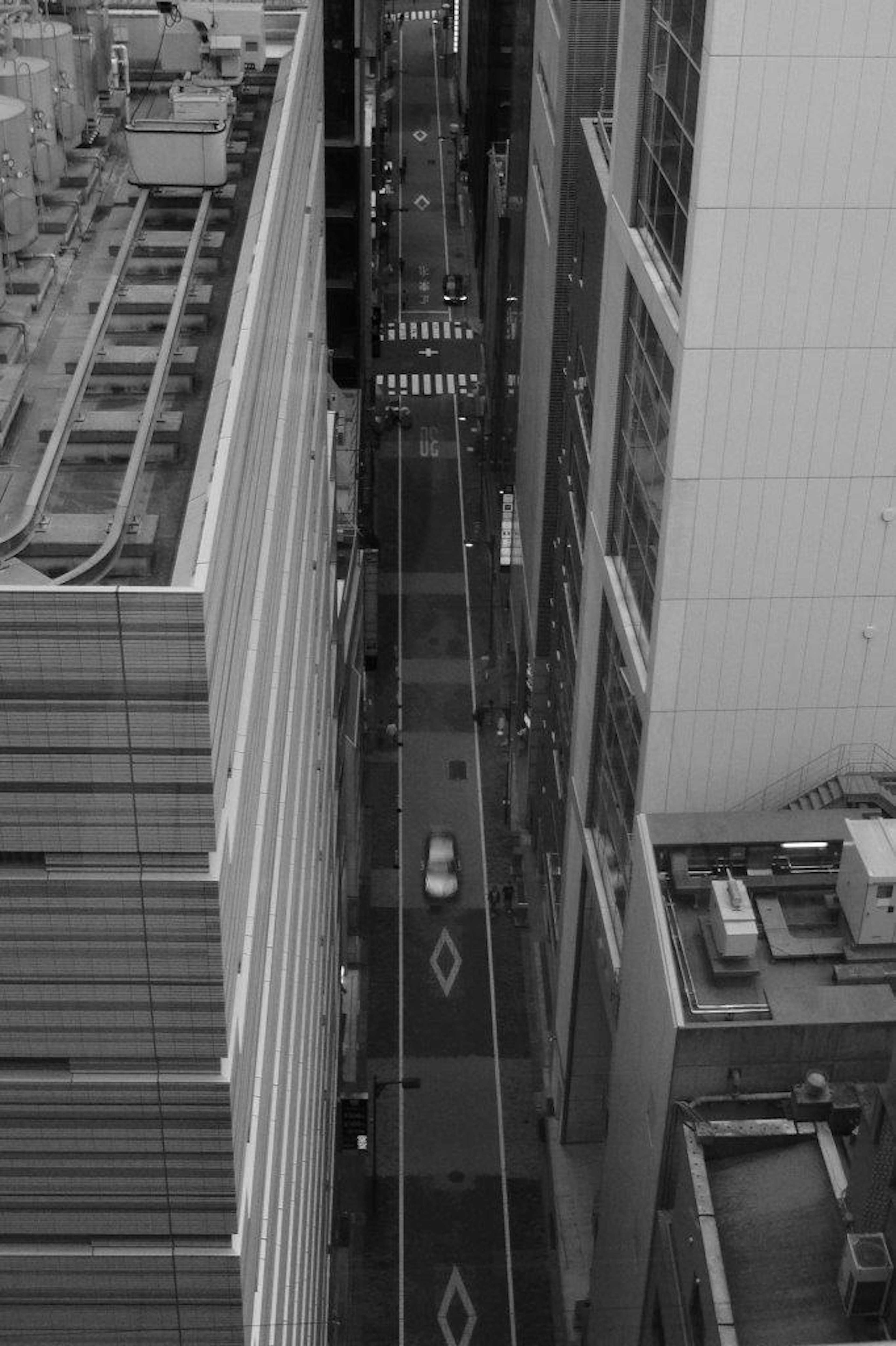 Black and white photo of a narrow street surrounded by skyscrapers