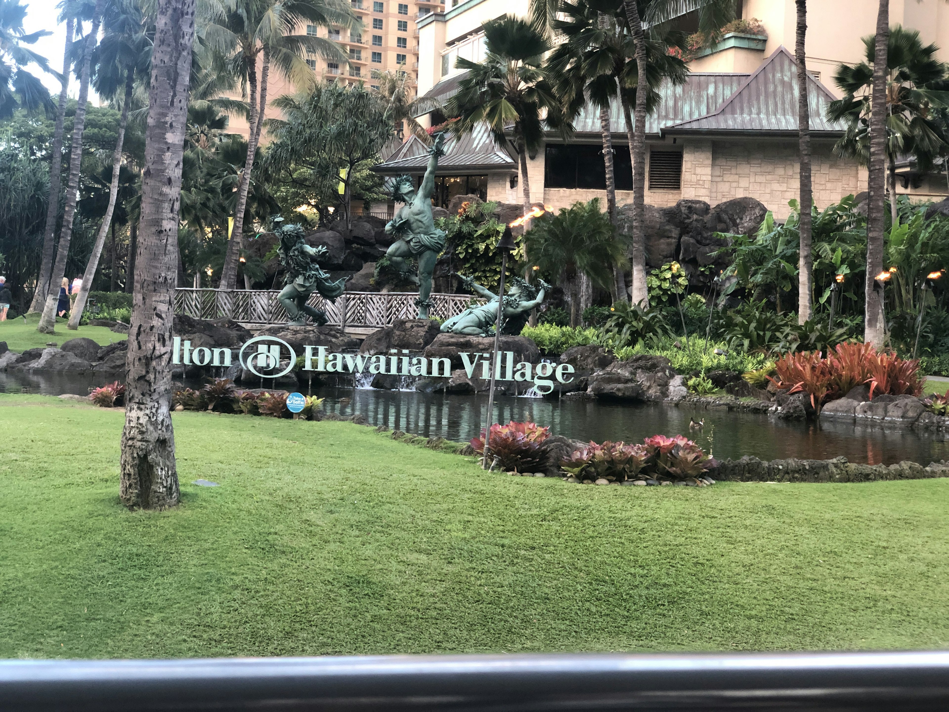 Hilton Hawaiian Village sign with lush garden landscape