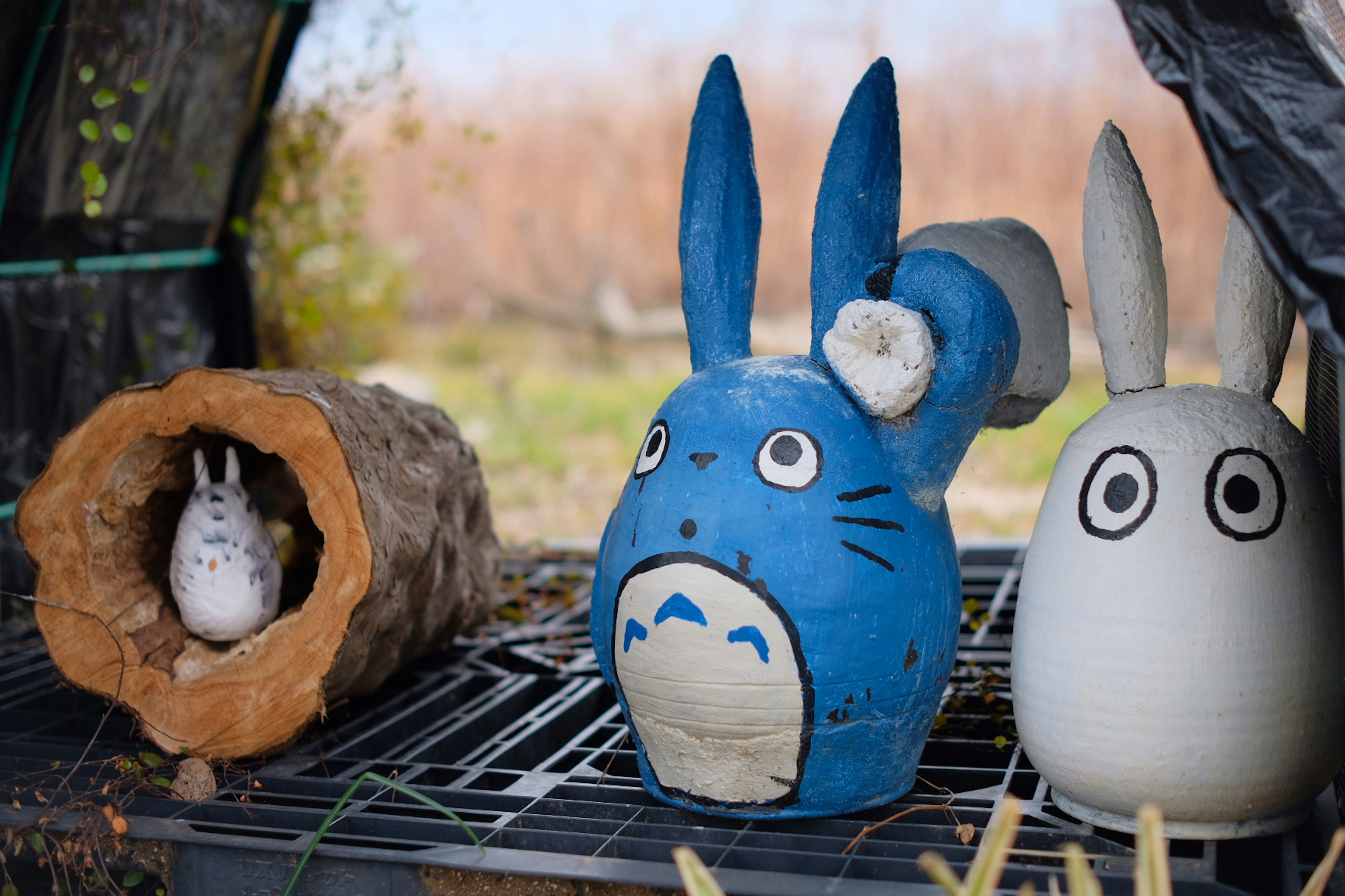 Una figura de cerámica de Totoro azul y una figura de conejo blanco expuestas juntas