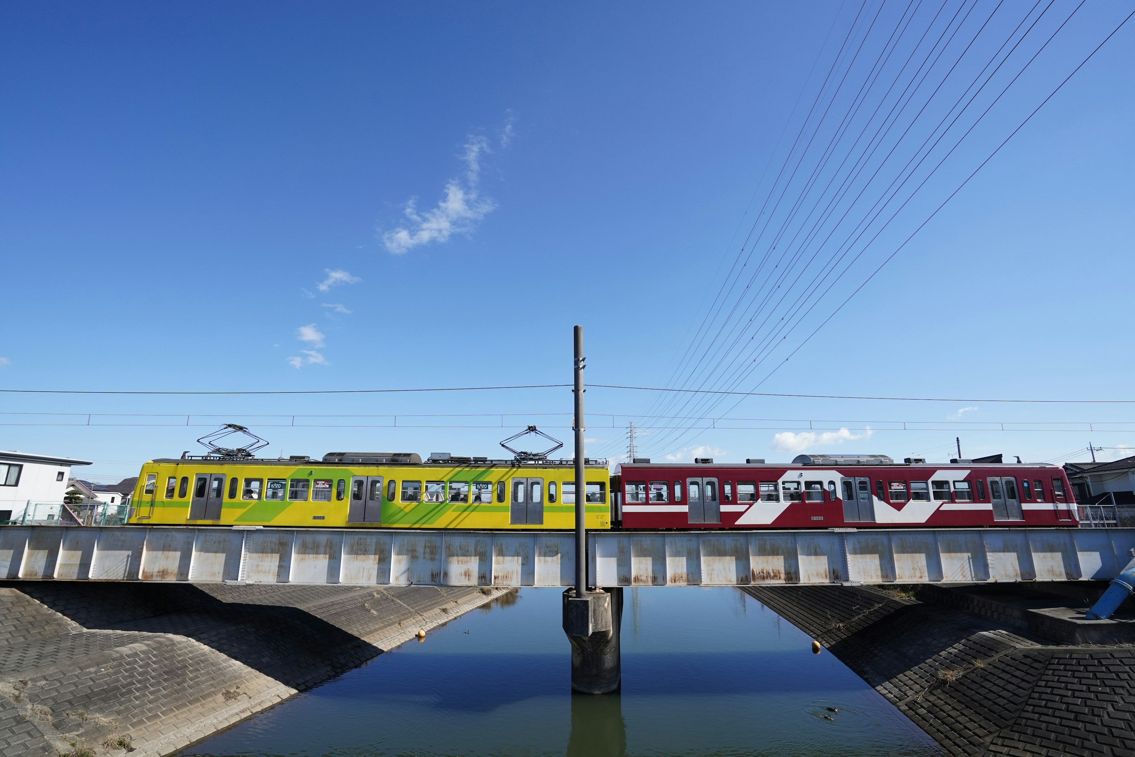 Vibrant yellow and red trains passing over a bridge