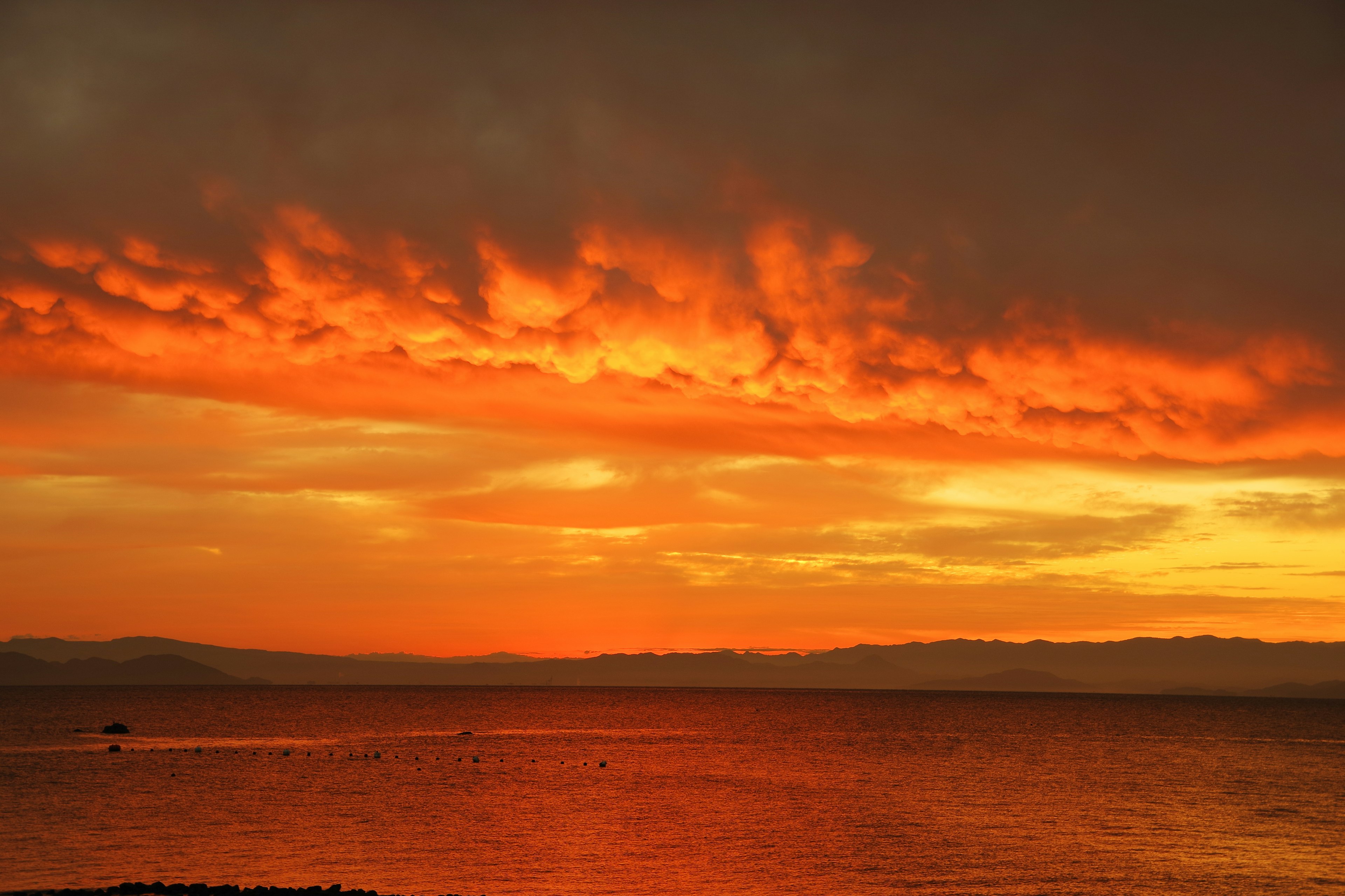 Wunderschöner orangefarbener Sonnenuntergang, der sich auf der Wasseroberfläche spiegelt