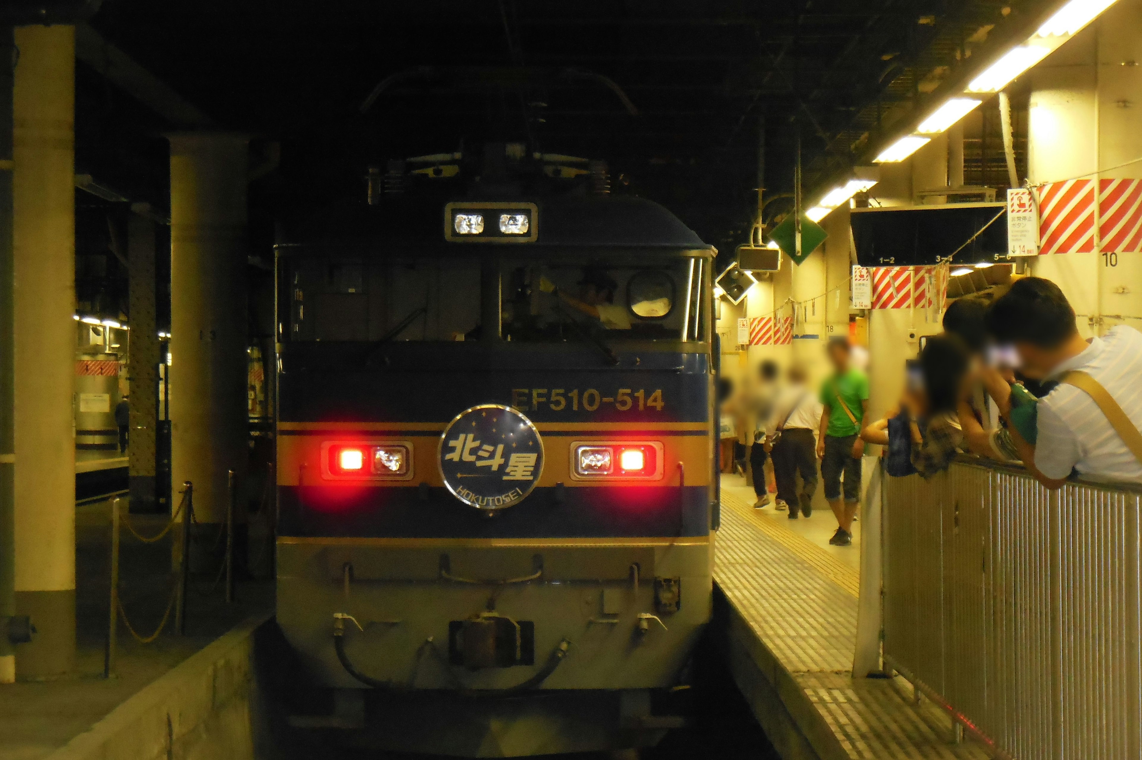 Train arrêté dans une station nocturne avec des passagers attendant