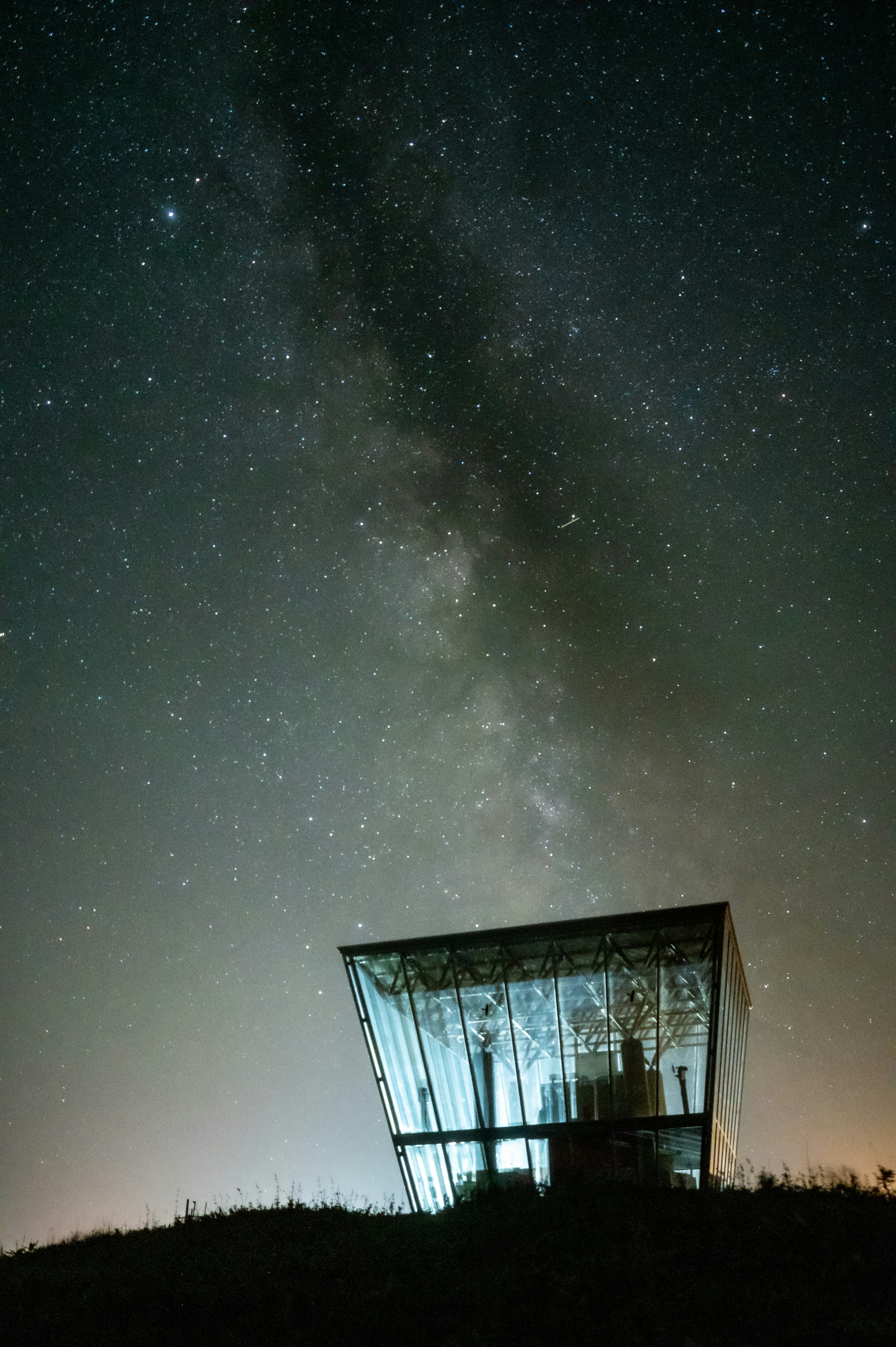 星空の下にある独特な形の建物と銀河の美しい景色