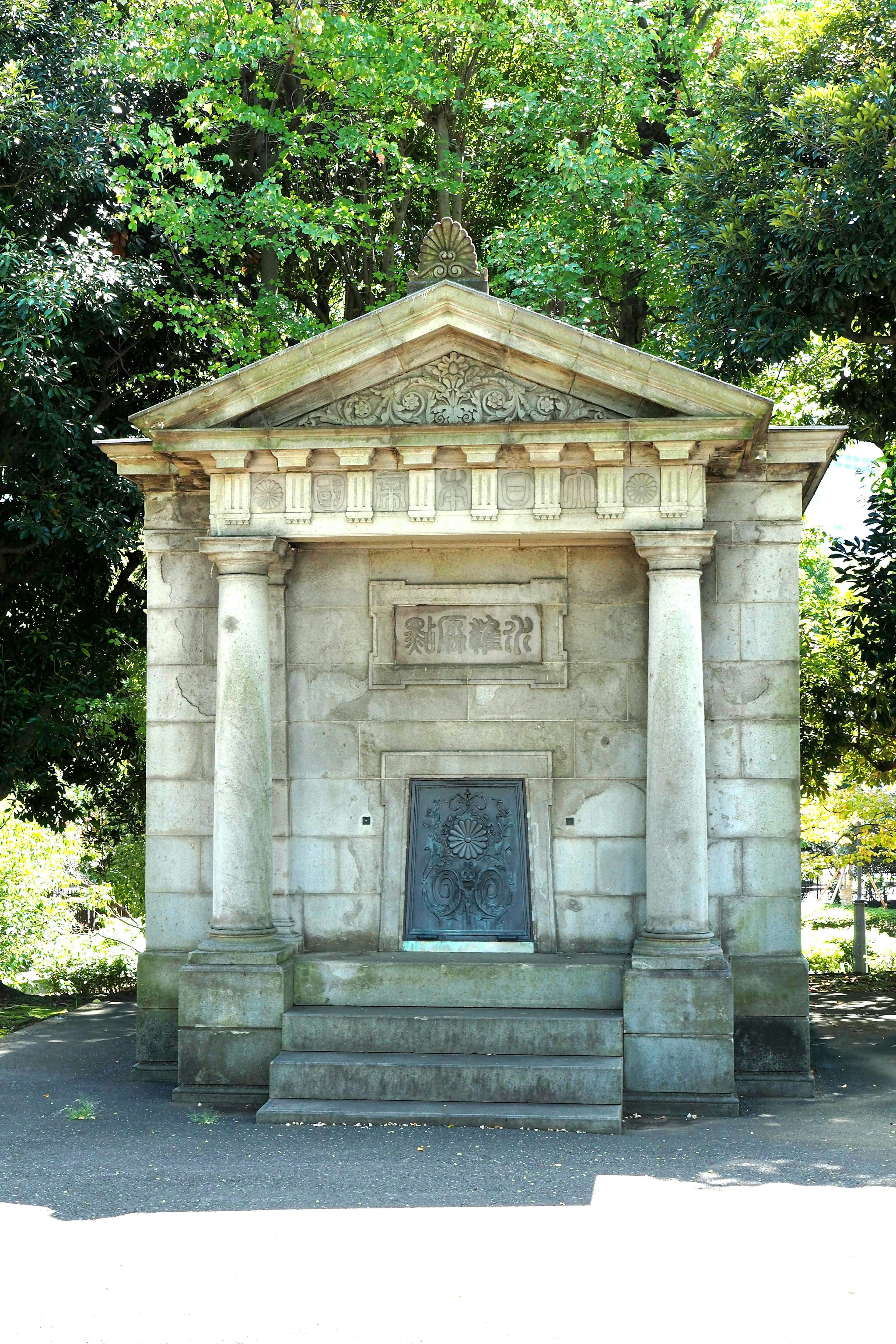 Classical stone structure with columns surrounded by greenery