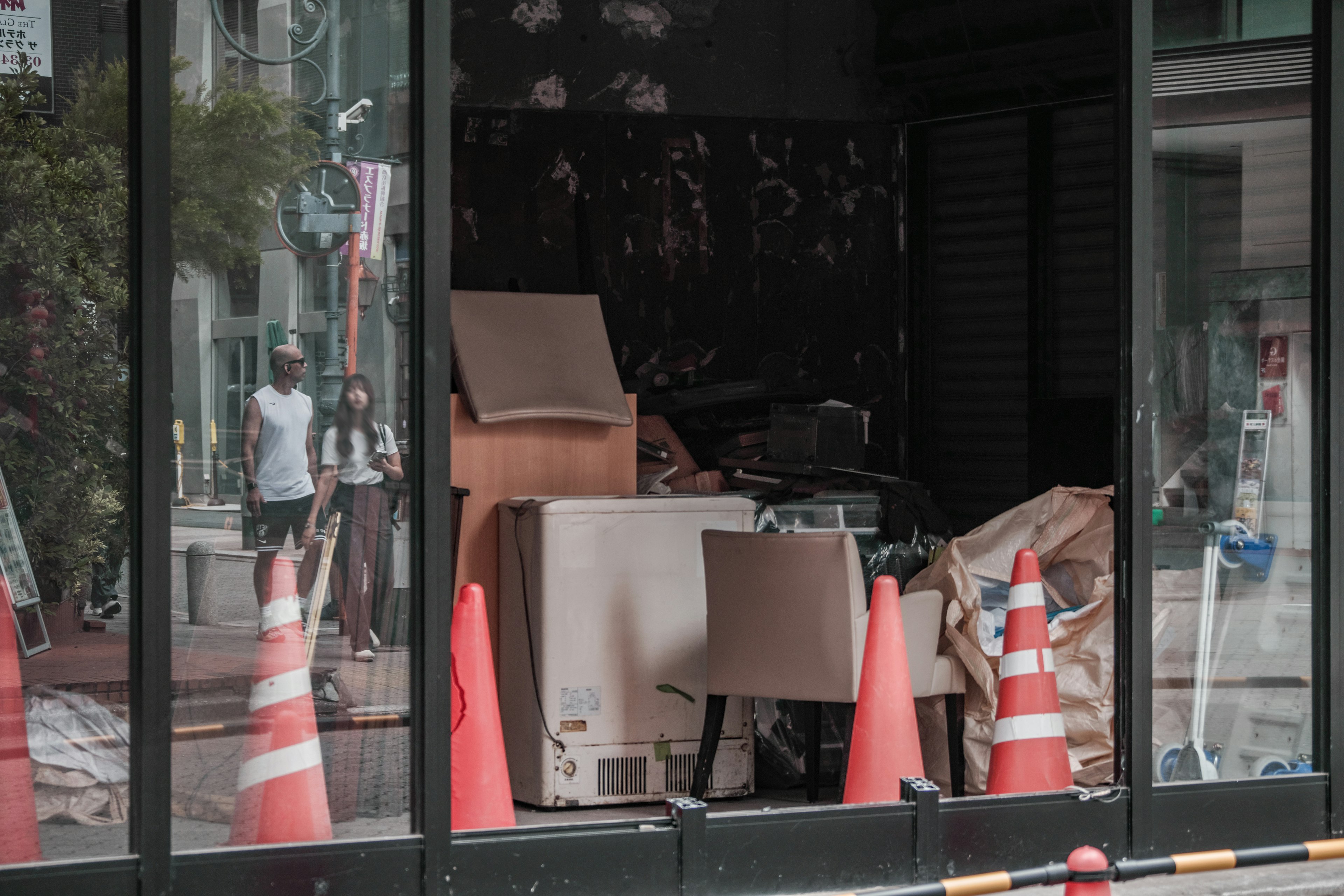 Unordentliches Interieur eines beschädigten Geschäfts sichtbar durch Glas mit orangefarbenen Kegeln