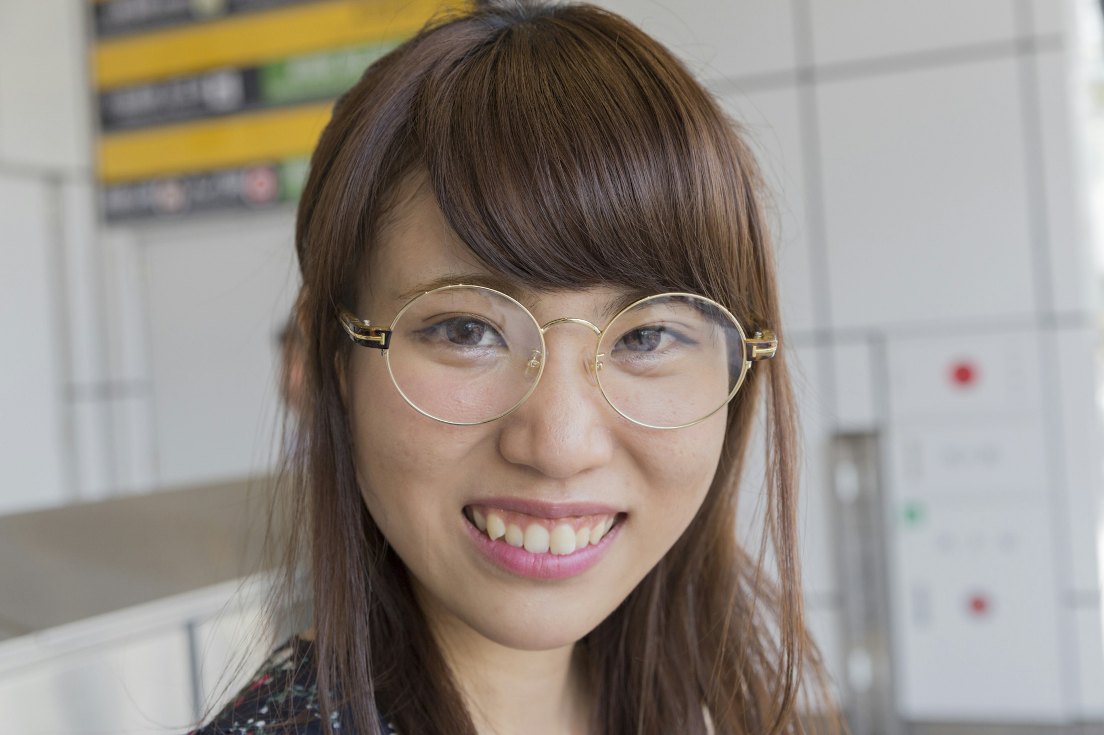 Smiling woman wearing glasses with a train station sign in the background