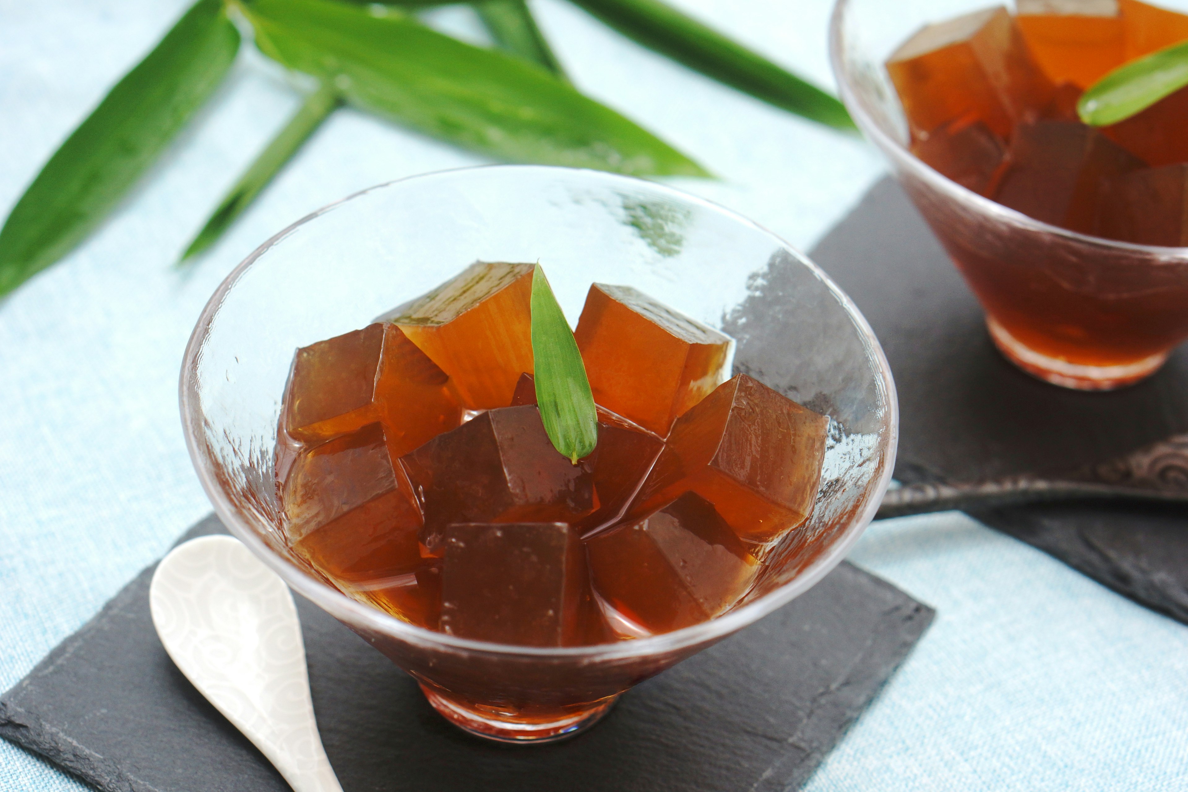 Postre de gelatina de coco en un tazón transparente con cubos de gelatina marrón decorados con hojas verdes