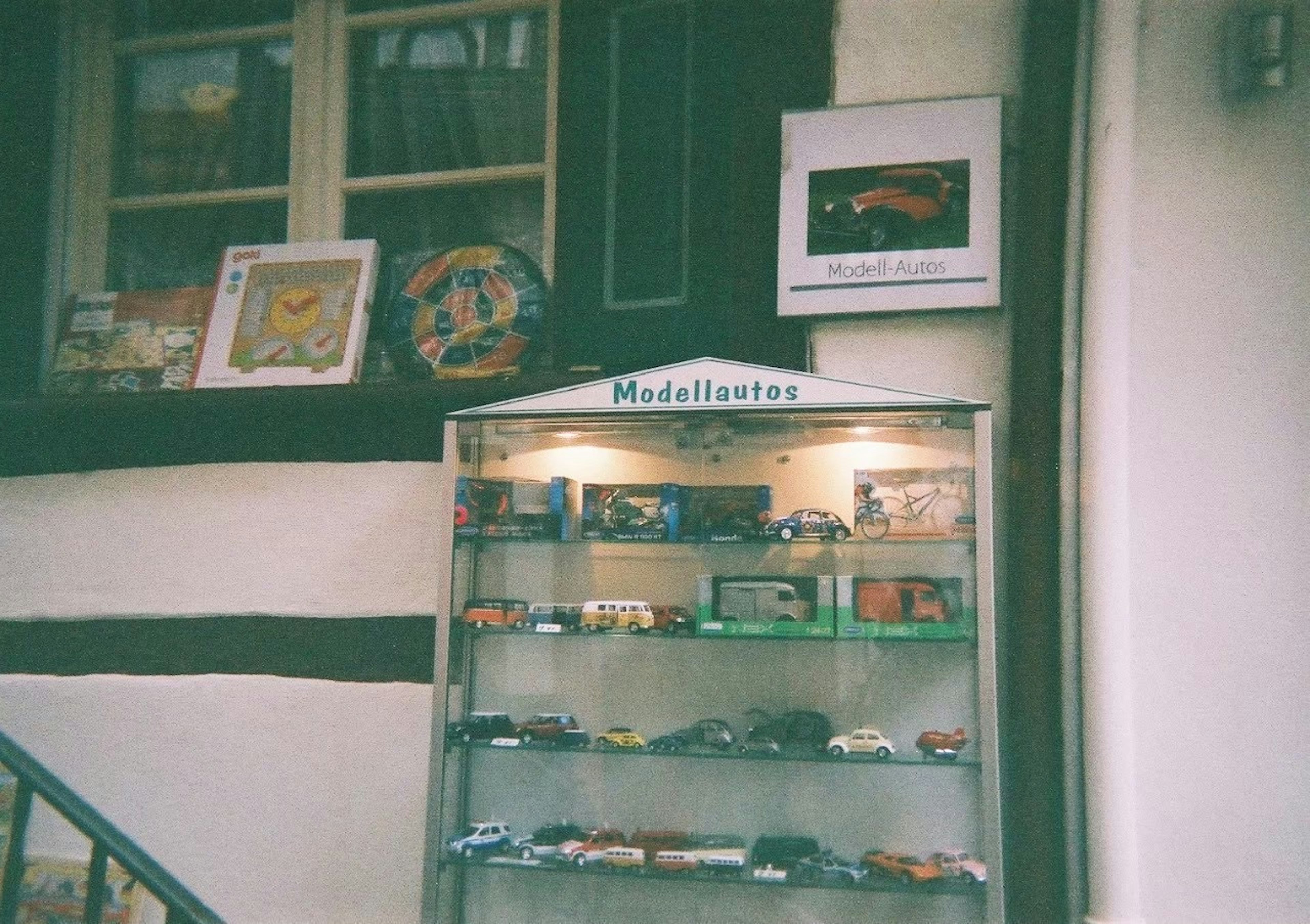 Showcase displaying miniature cars and artwork on the wall