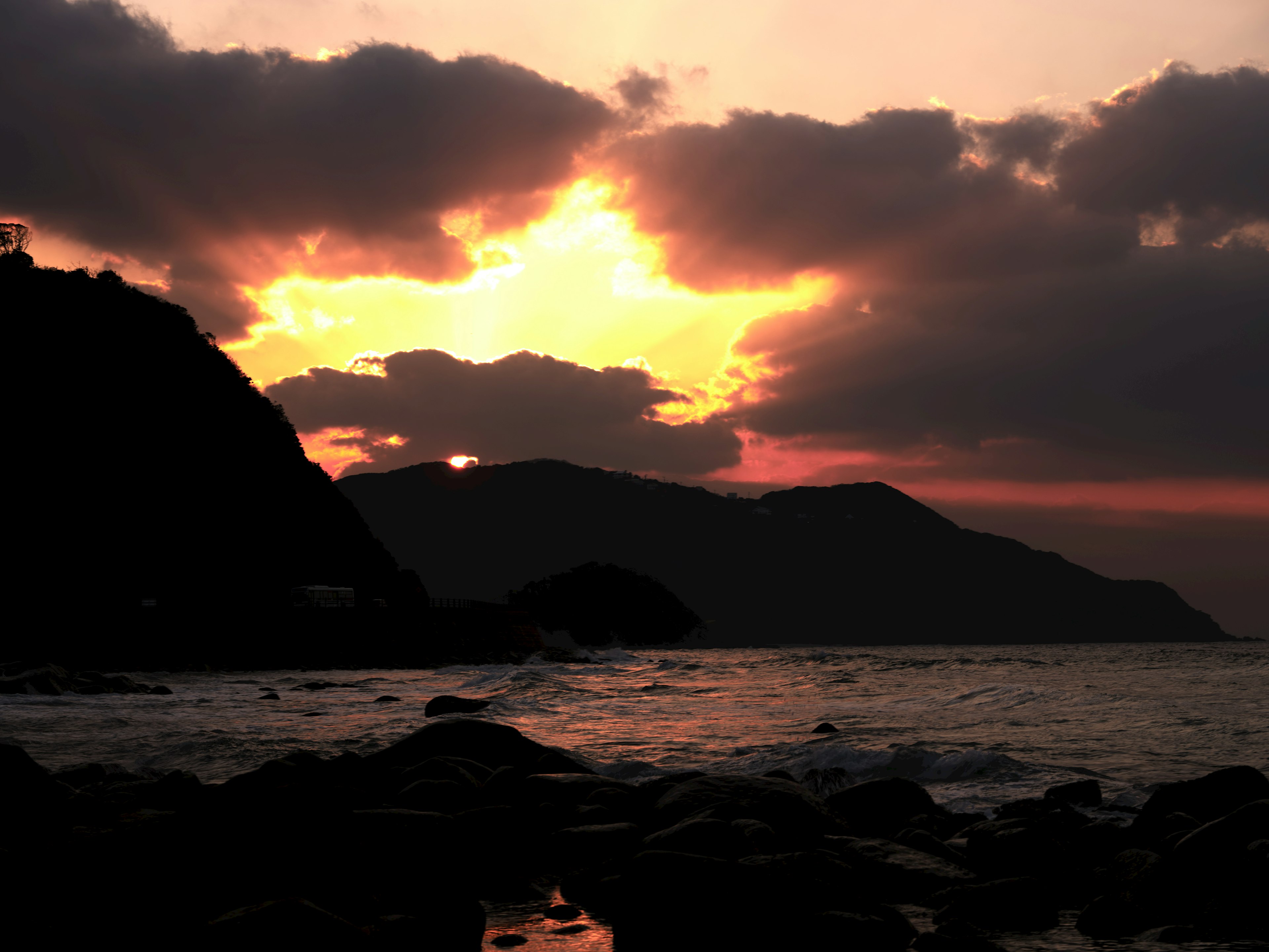 夕日が雲の間から差し込む海岸の風景