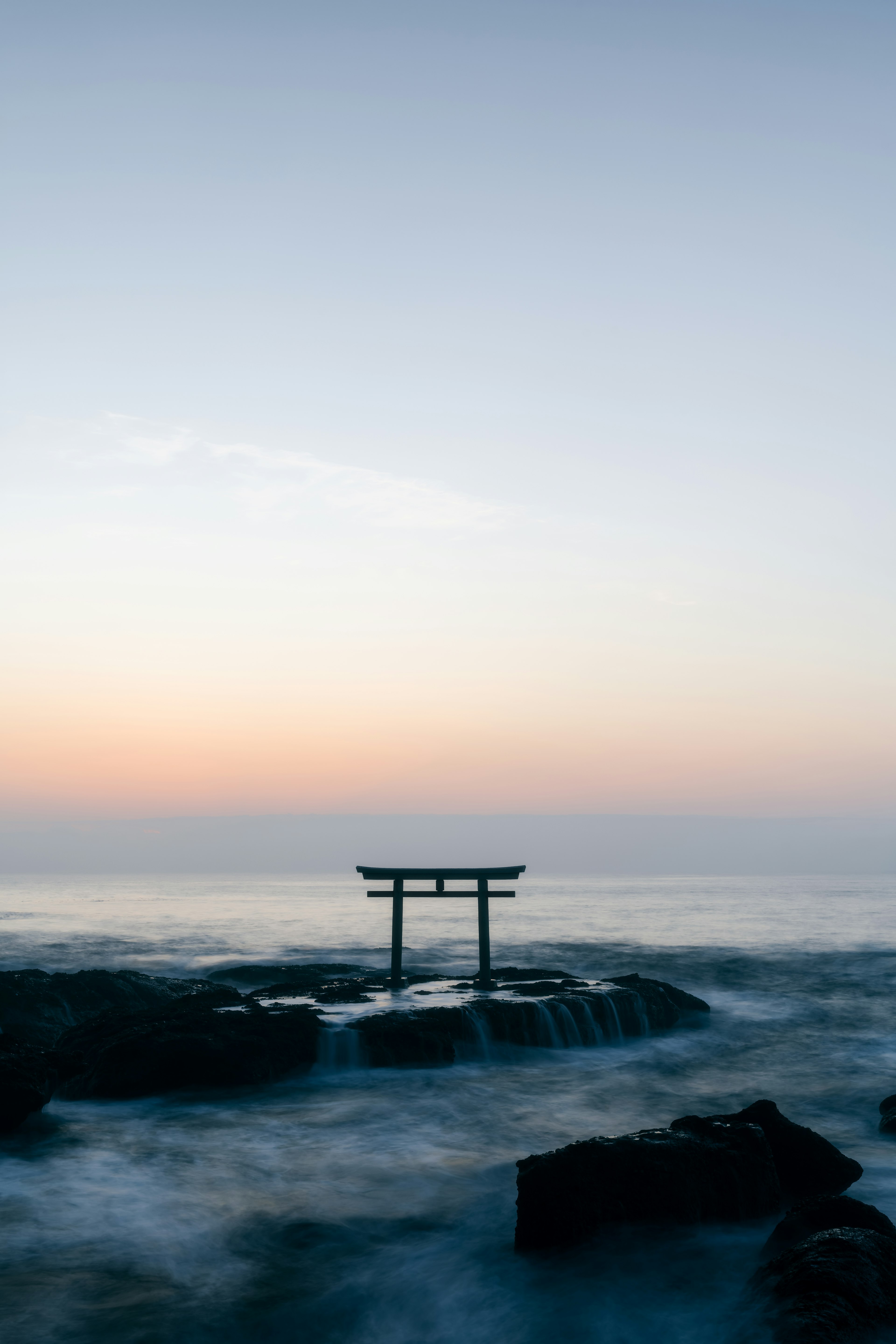 Torii ที่ชายทะเลในช่วงพระอาทิตย์ตกที่เงียบสงบ