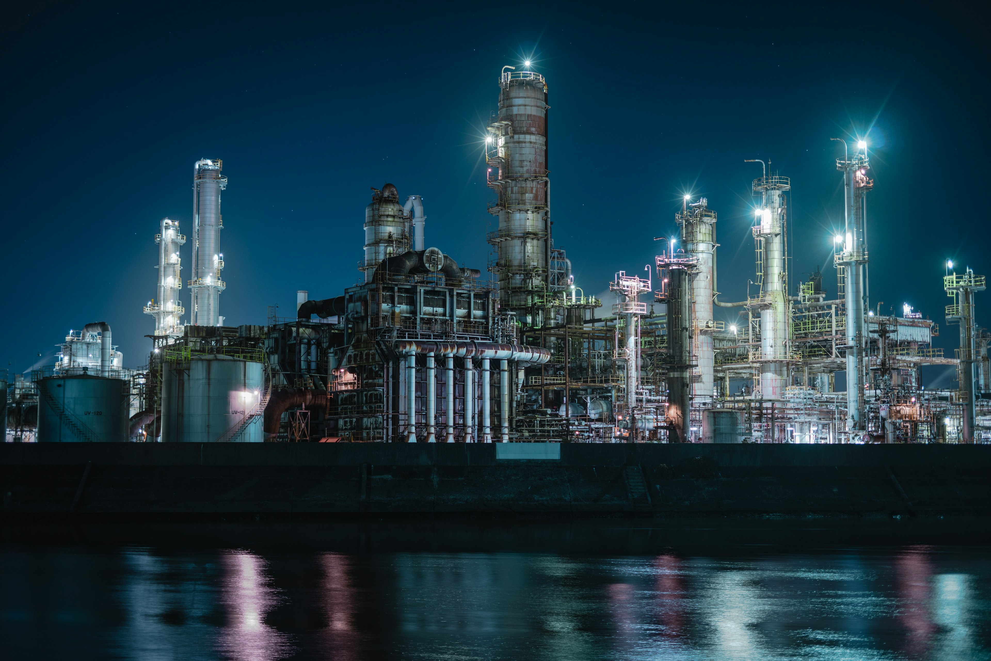 Industrial landscape at night featuring factory smokestacks and bright lights