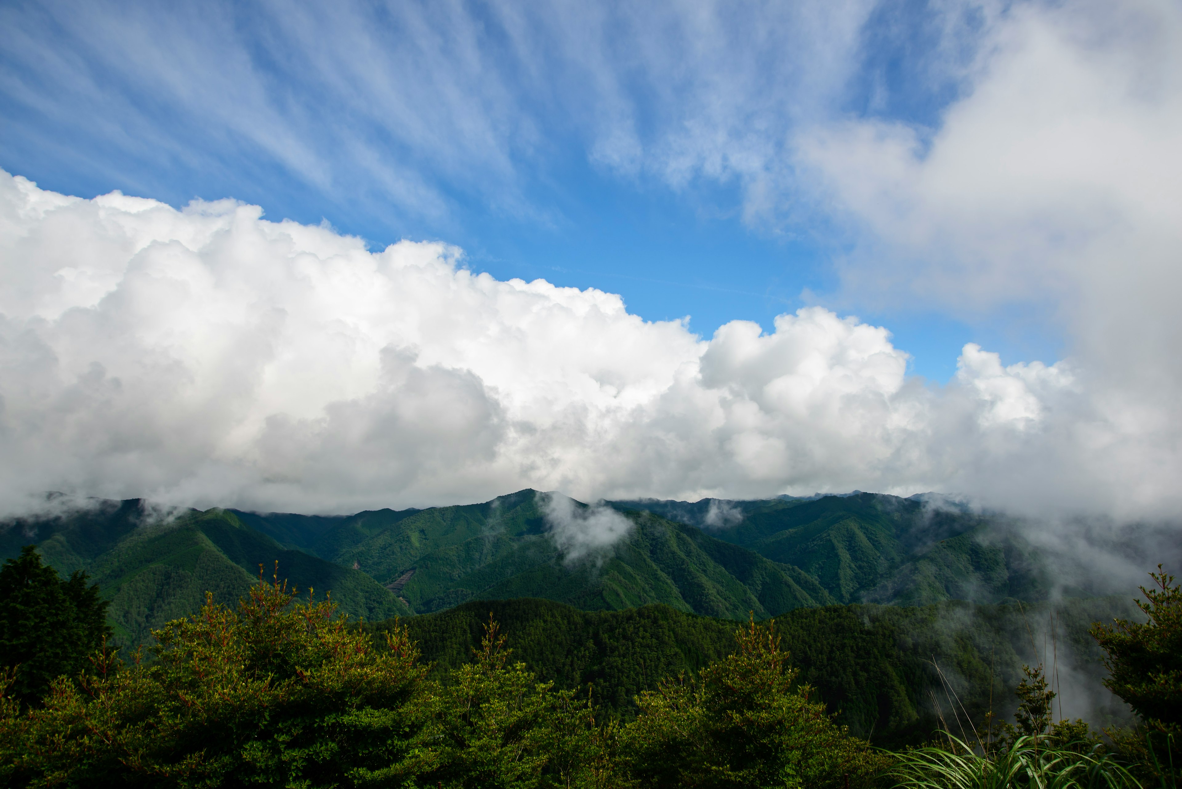 青空と白い雲が広がる山の風景 緑の木々と山々が美しい