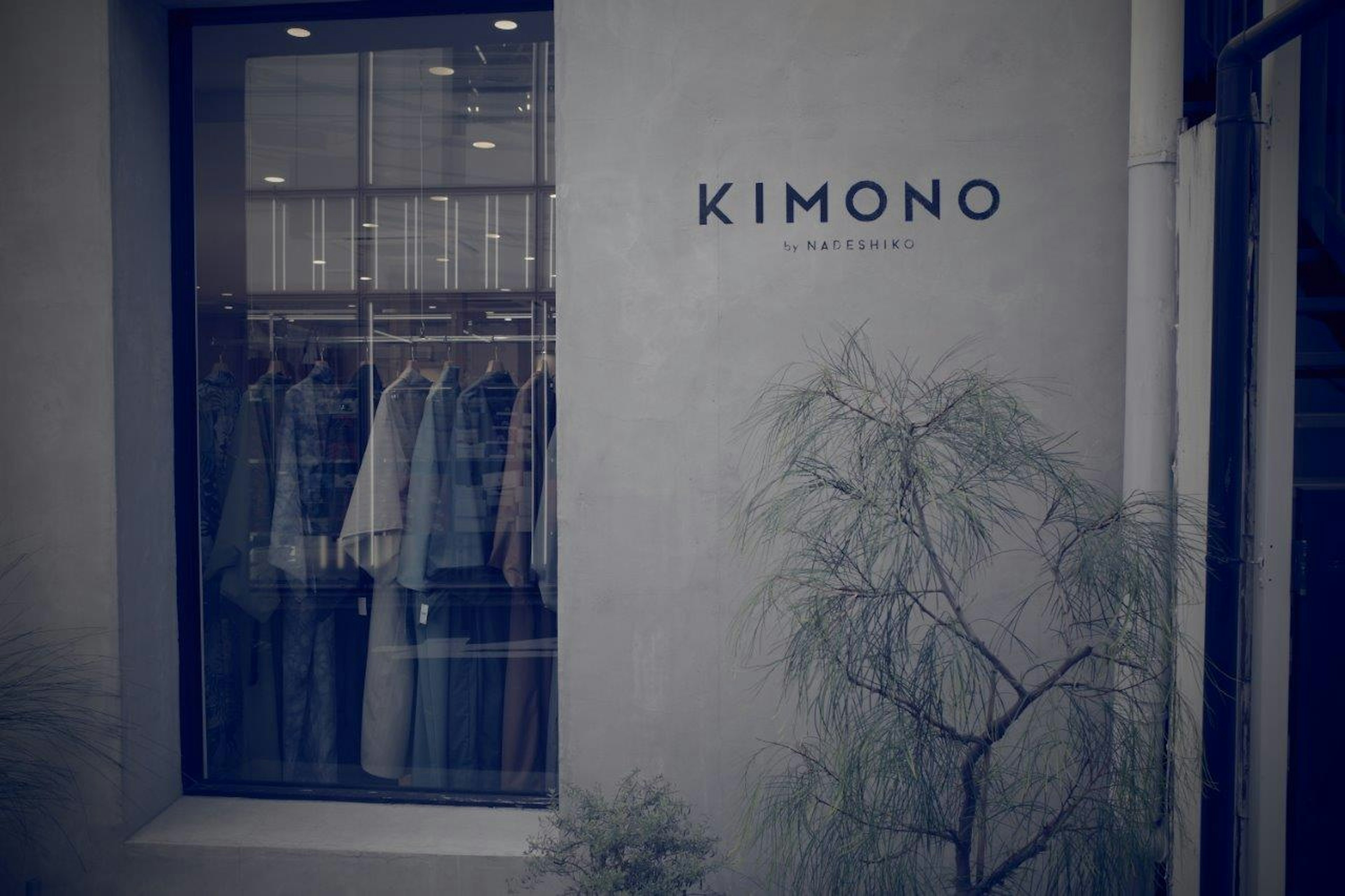 「KIMONO」の看板がある店舗の外観で、店内には衣服が掛けられている