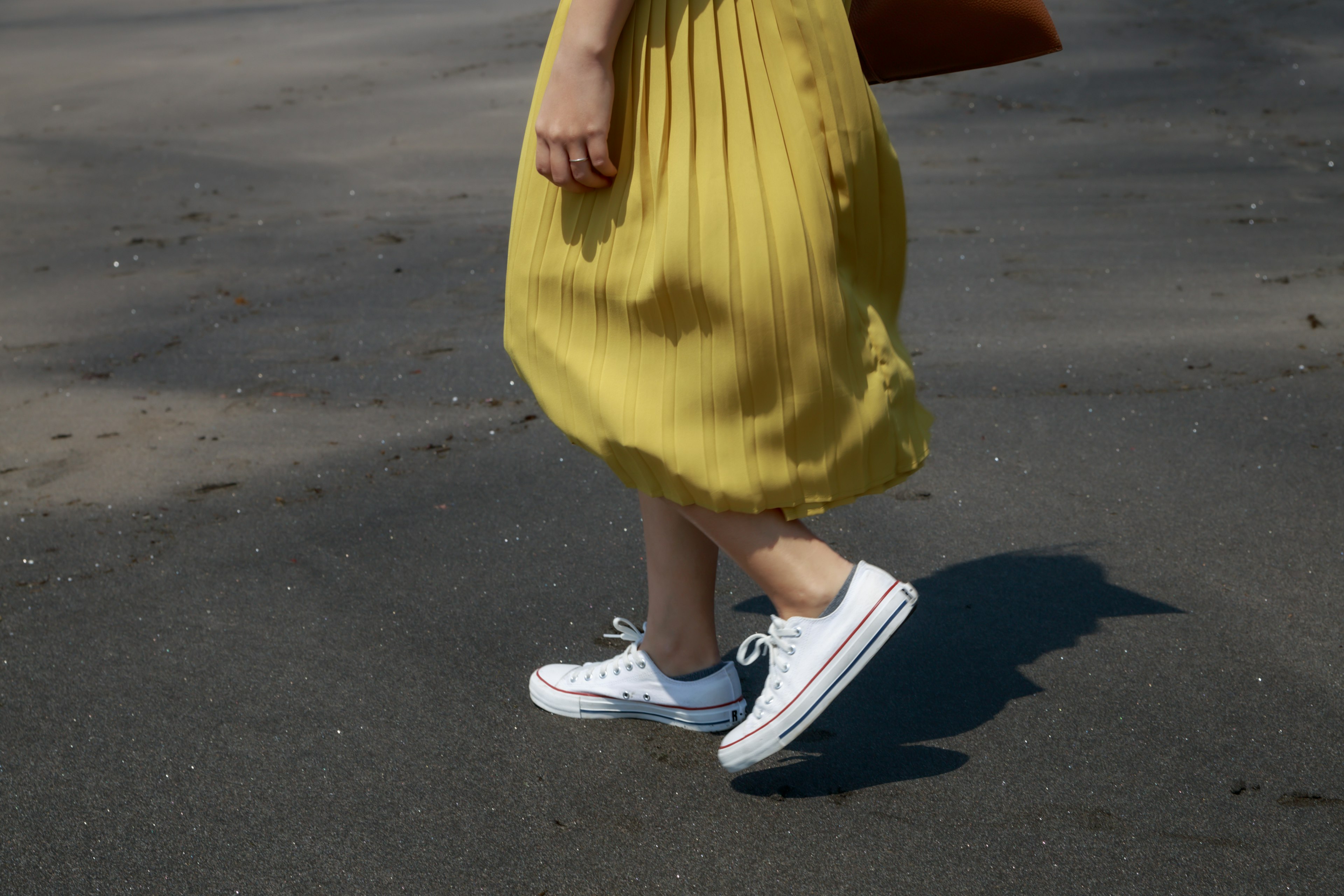 Una mujer con un vestido amarillo caminando en zapatillas blancas