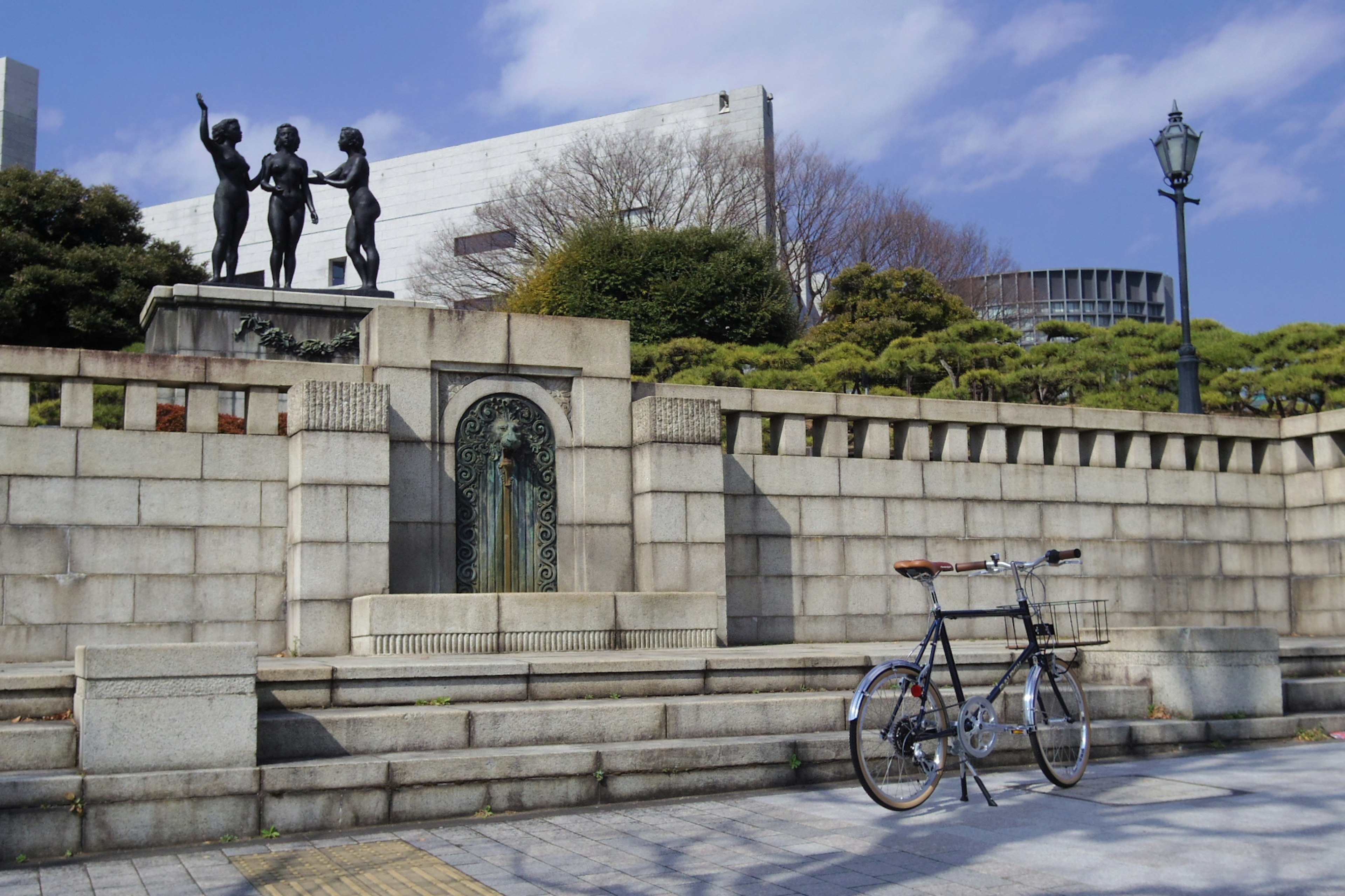 公園の石の壁の前に自転車が置かれた風景と彫像