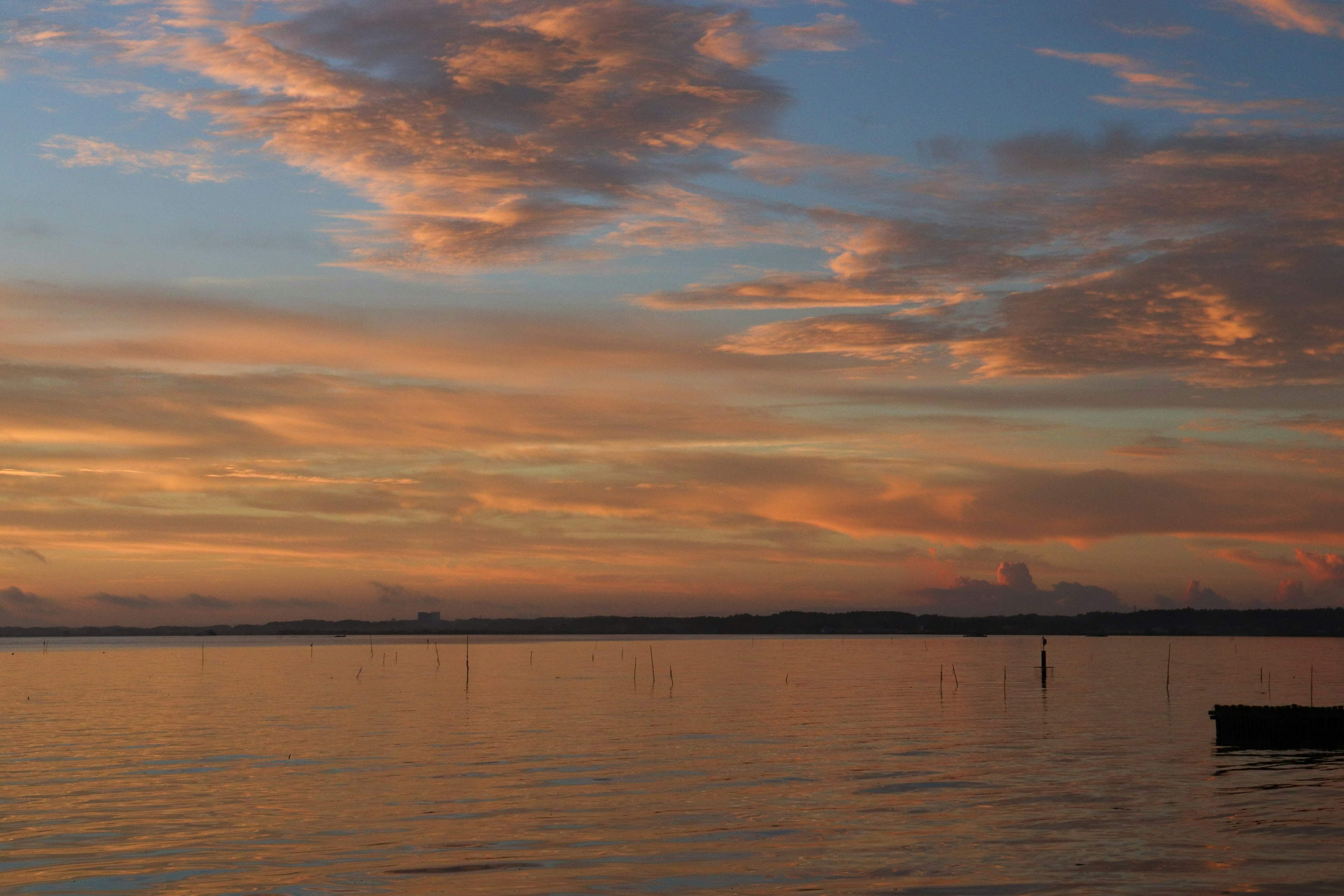 Ruhiger See, der einen Sonnenuntergangshimmel mit Wolken spiegelt