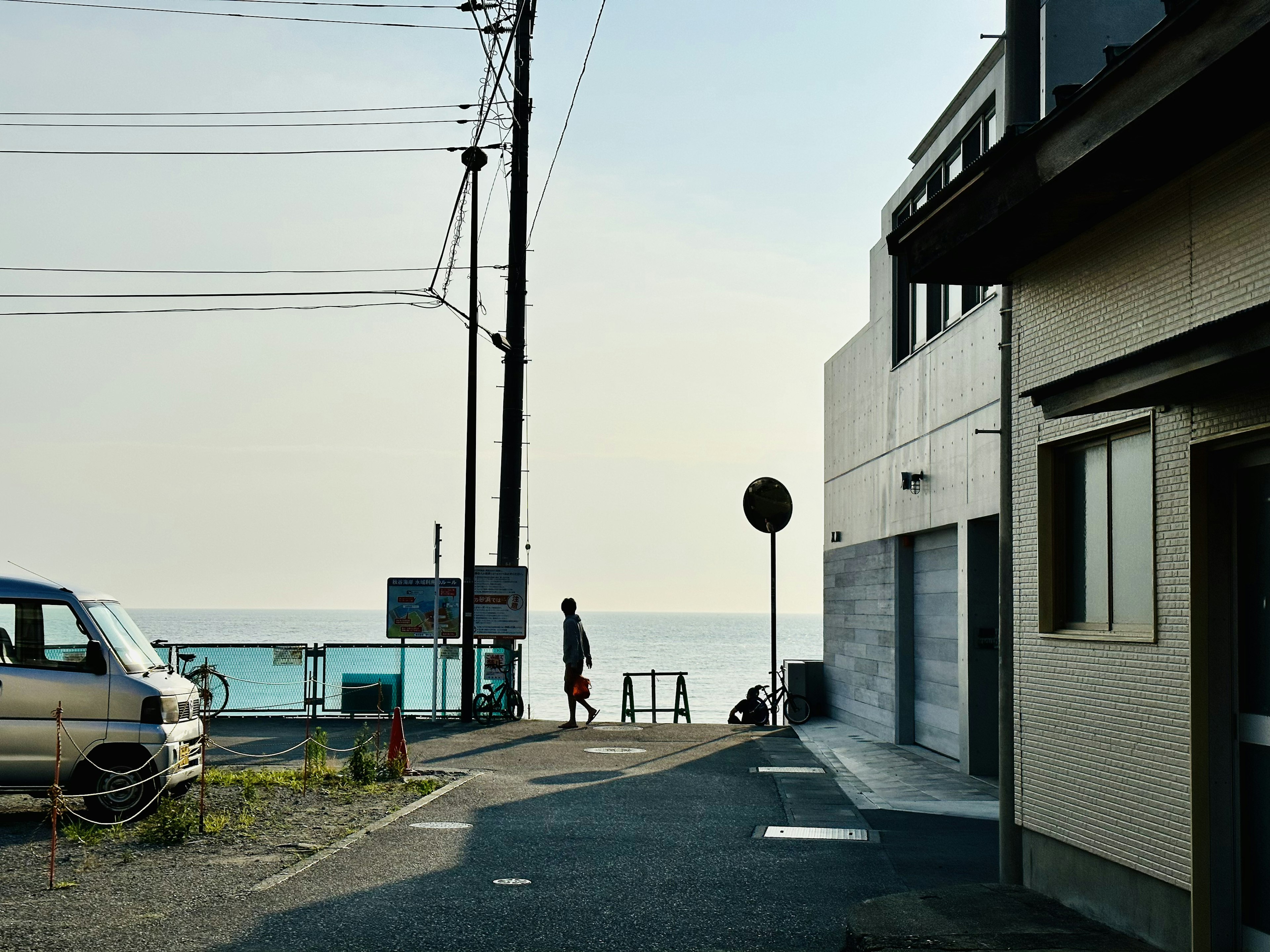 静かな海岸の道に立つ人影と海の景色