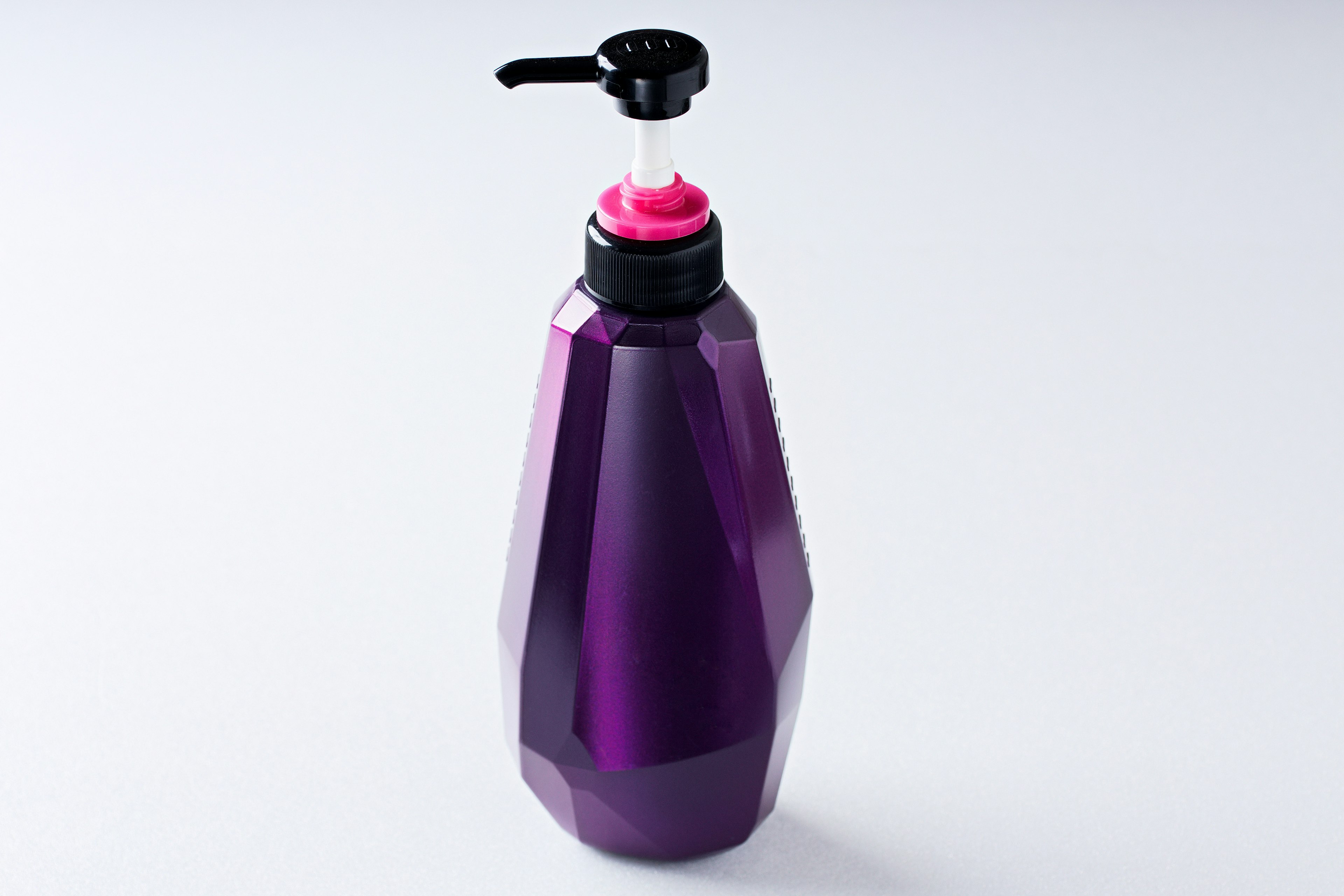 Bouteille géométrique violette avec pompe noire et capuchon rose