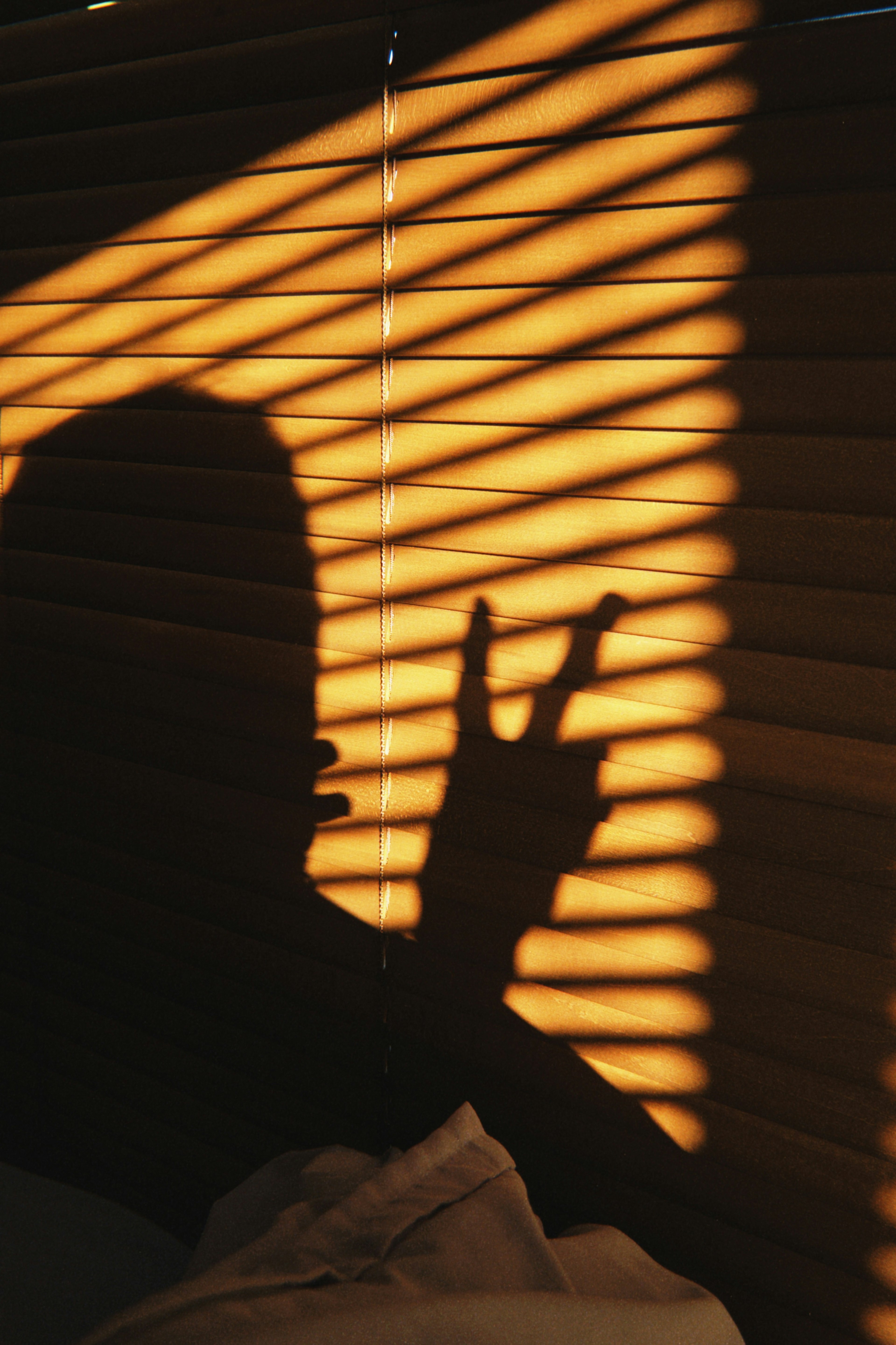 Silhouette of a hand against striped shadows from blinds