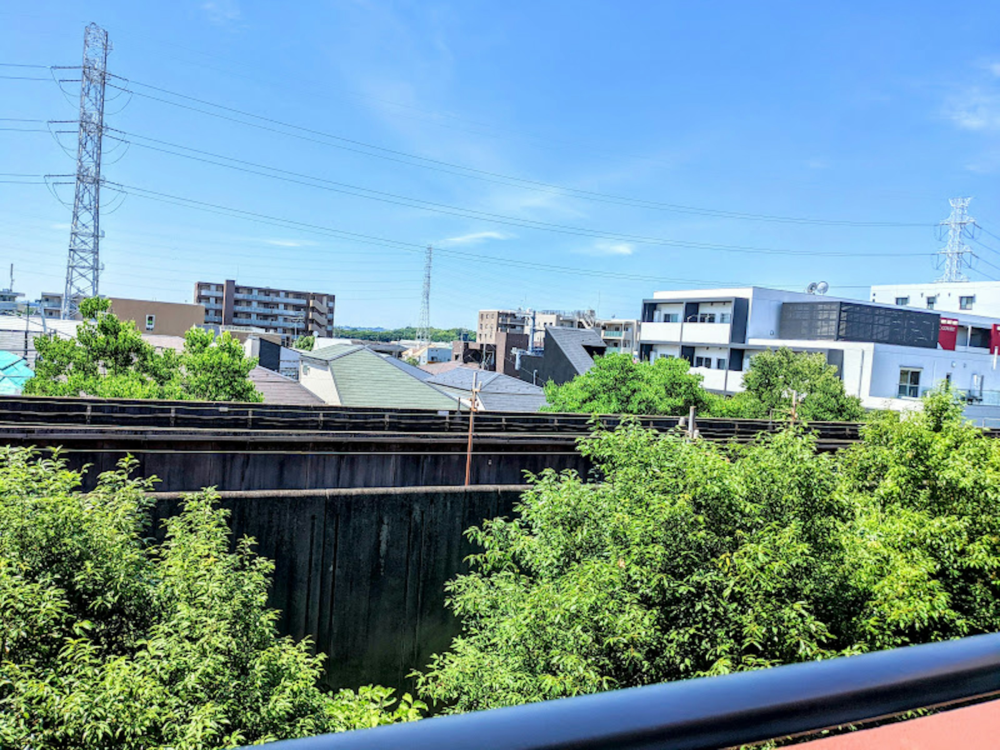 Urban landscape under blue sky featuring railway tracks and lush greenery