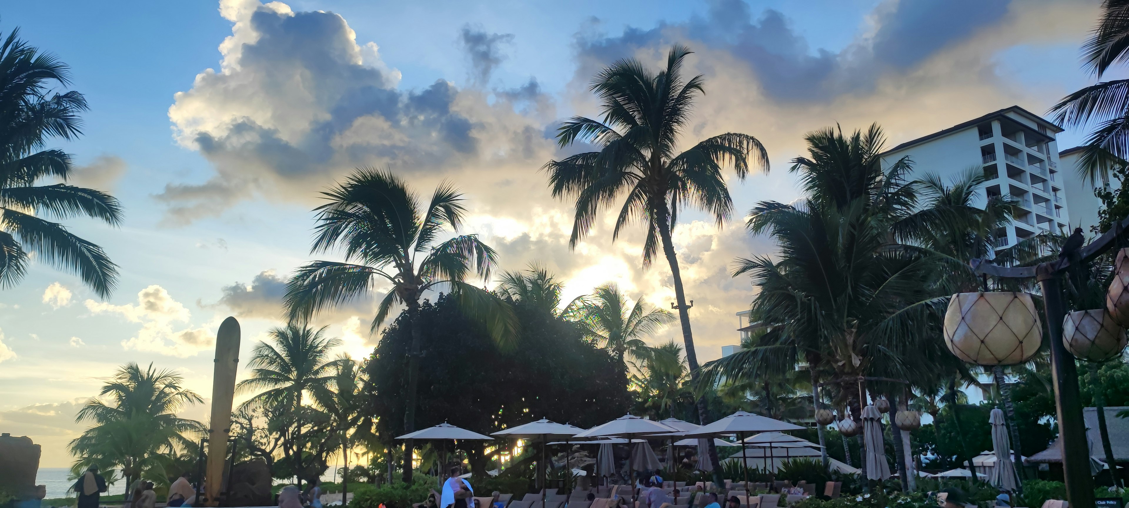 Scena di un resort sulla spiaggia al tramonto con palme e lettini