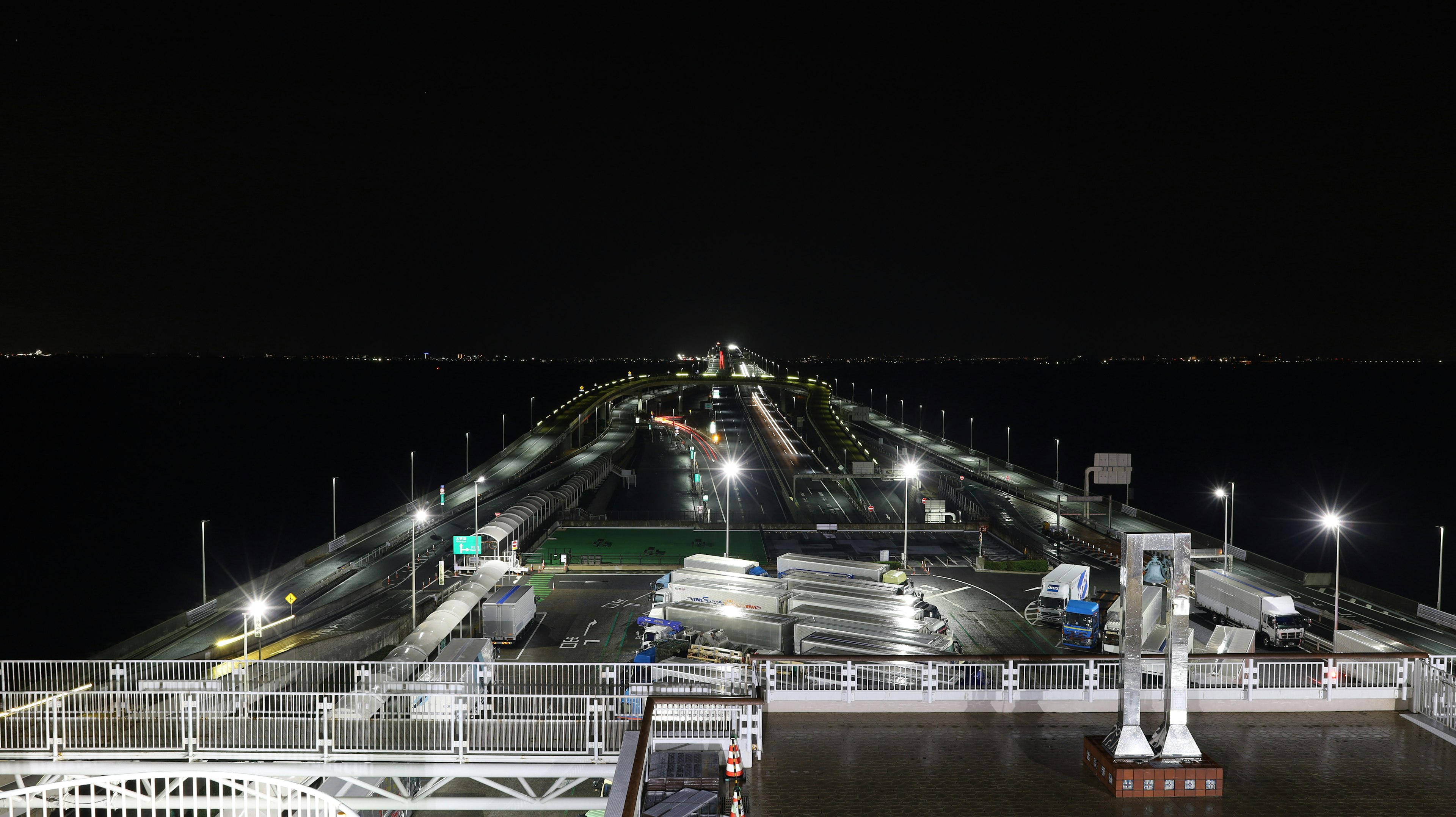 A serene view of a long pier at night with lights illuminating the path