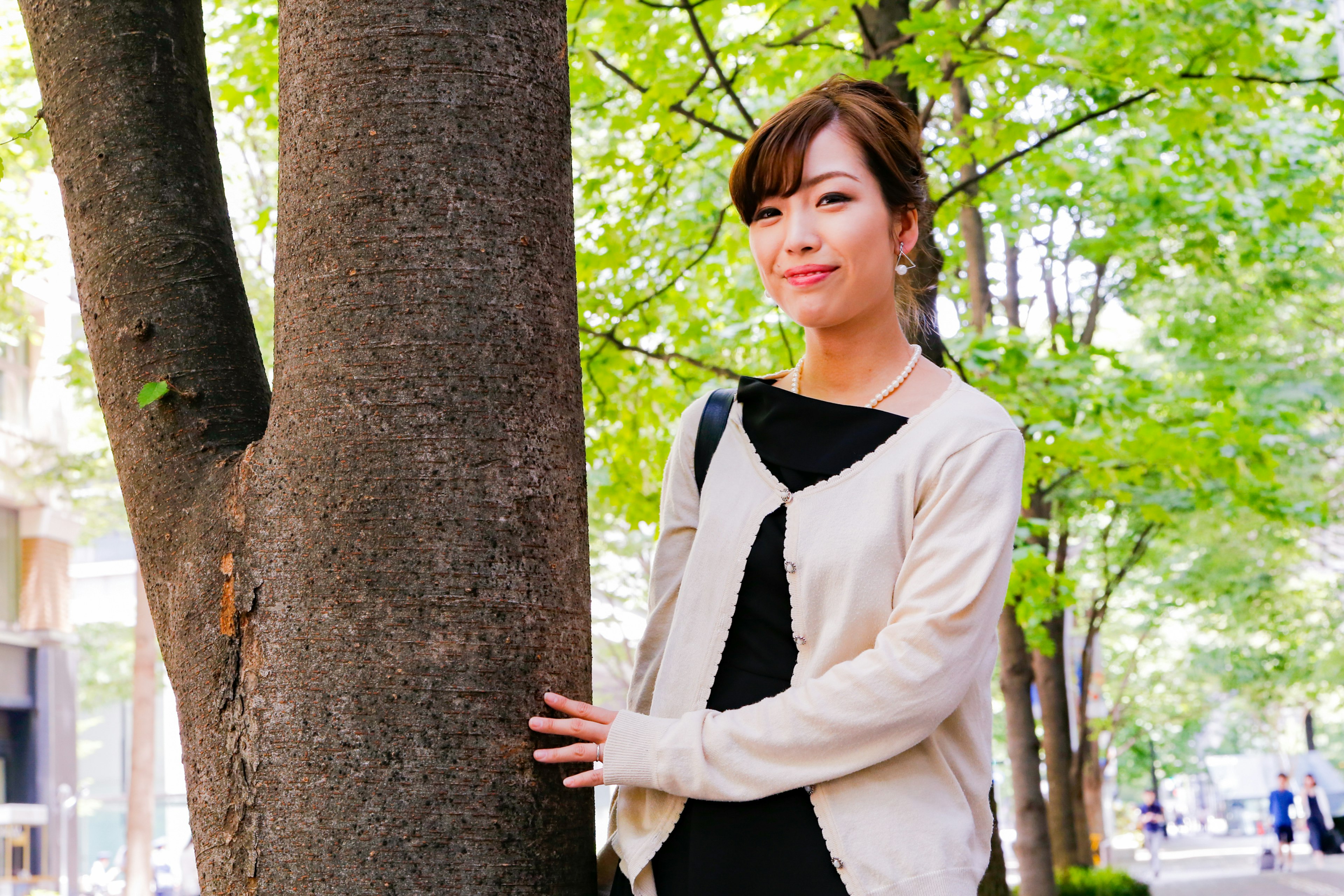 Femme souriante à côté d'un arbre dans un parc verdoyant