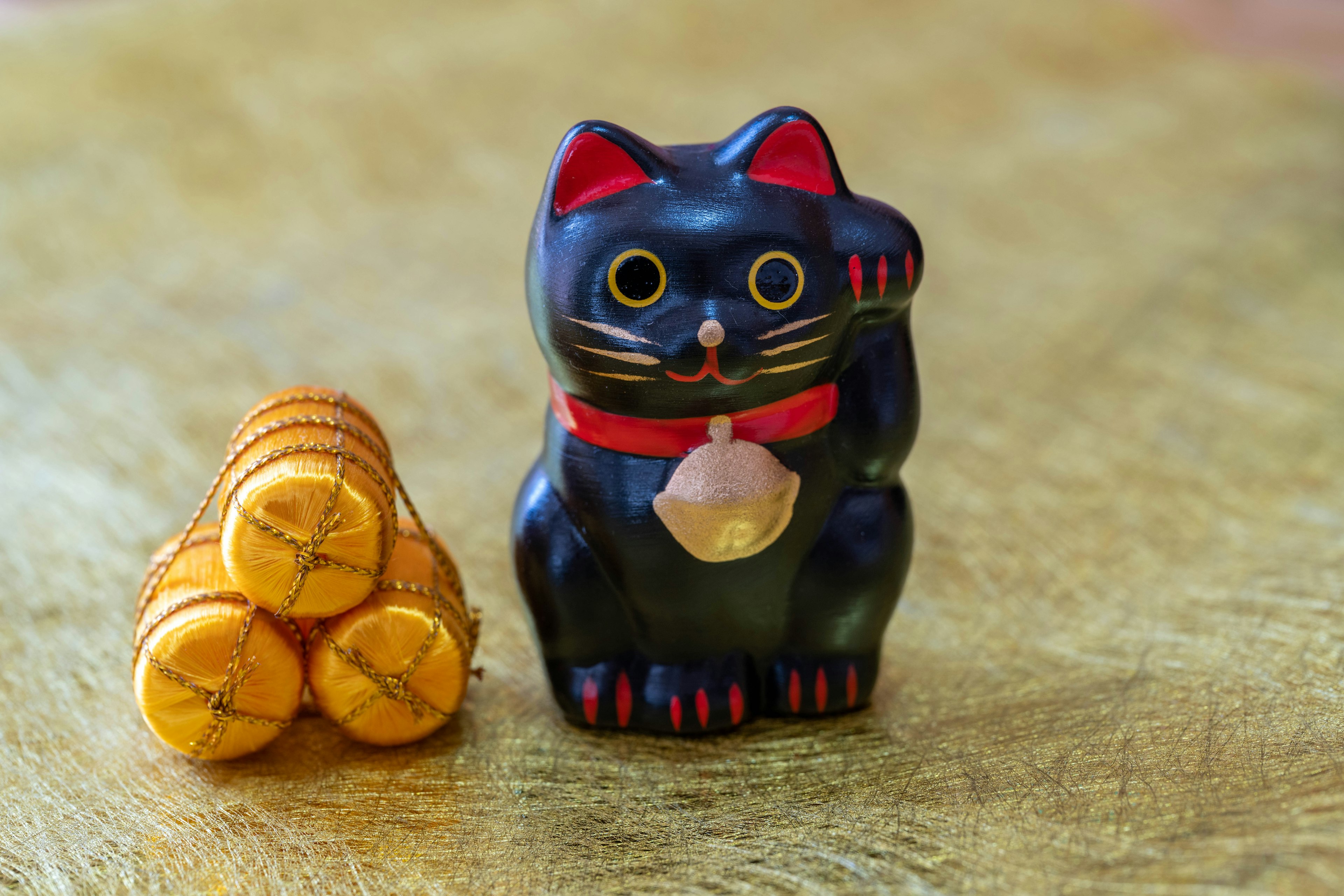 Figura de gato negro de la suerte junto a una pila de monedas naranjas