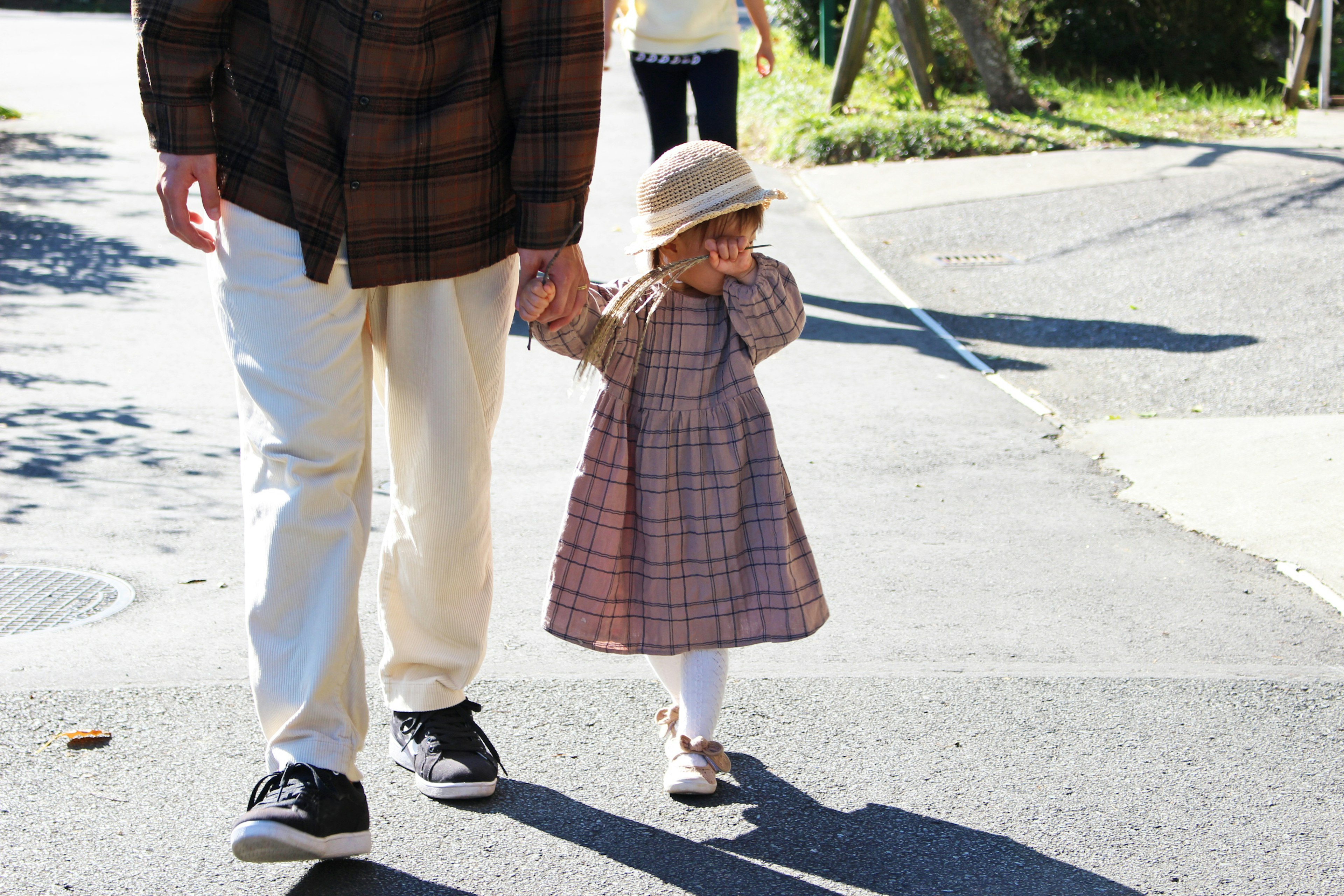 Una niña pequeña caminando de la mano de su padre en un día soleado