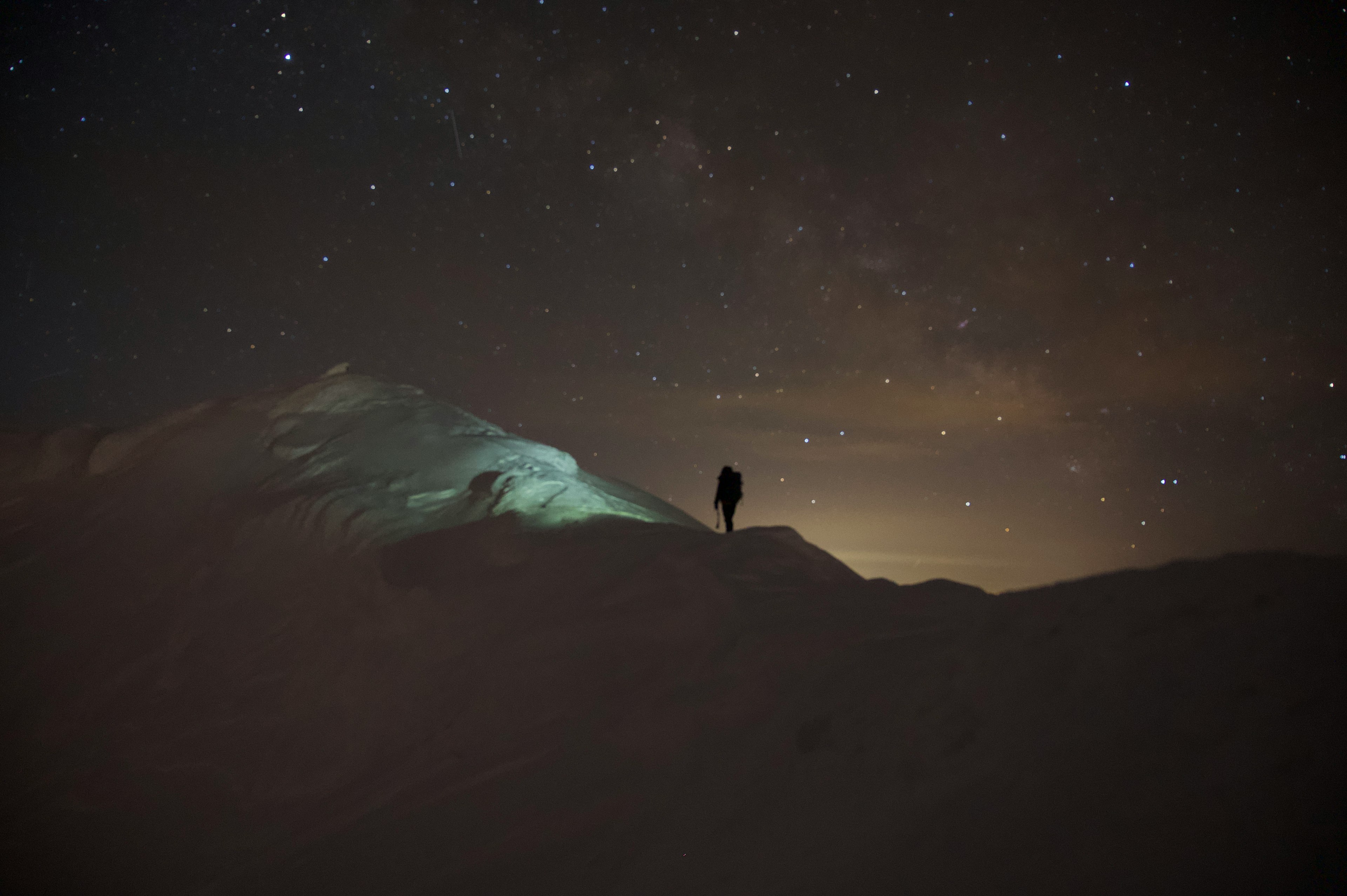 星空の下に立つ一人の登山者と山の景色