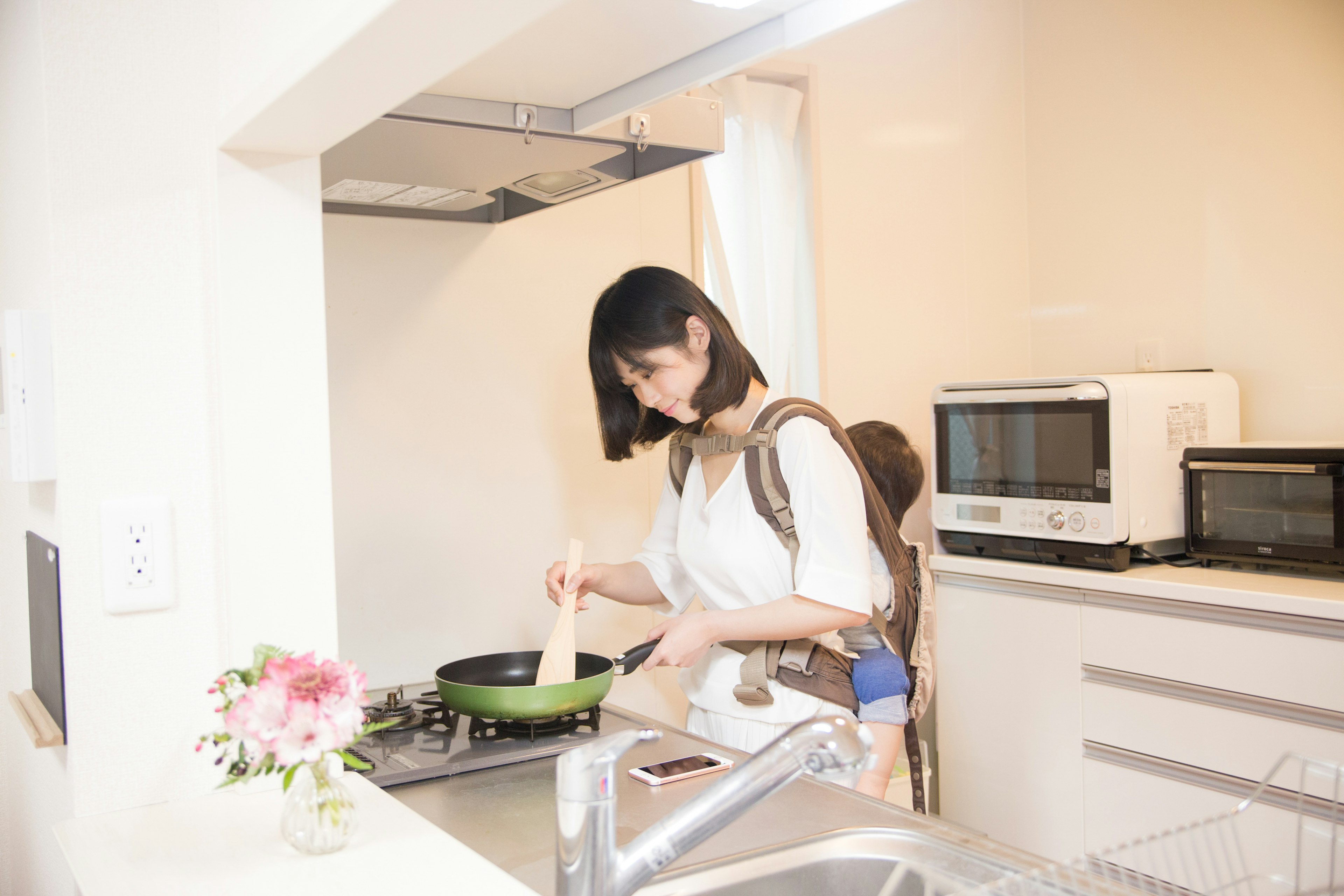 Une femme remuant une casserole dans une cuisine lumineuse avec des appareils modernes