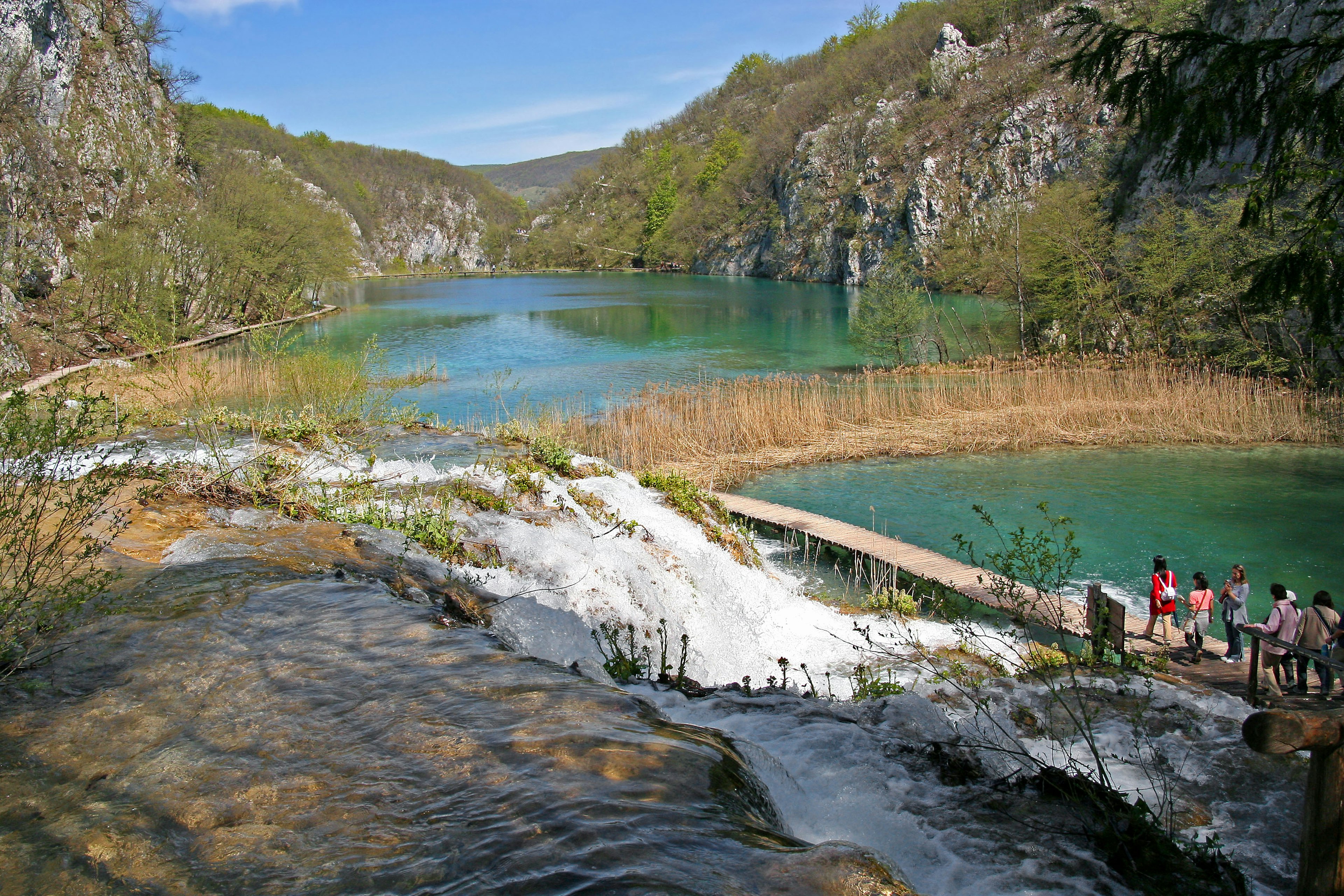 ทิวทัศน์ที่สวยงามของทะเลสาบสีน้ำเงินและน้ำตกที่ล้อมรอบด้วยความเขียวขจี