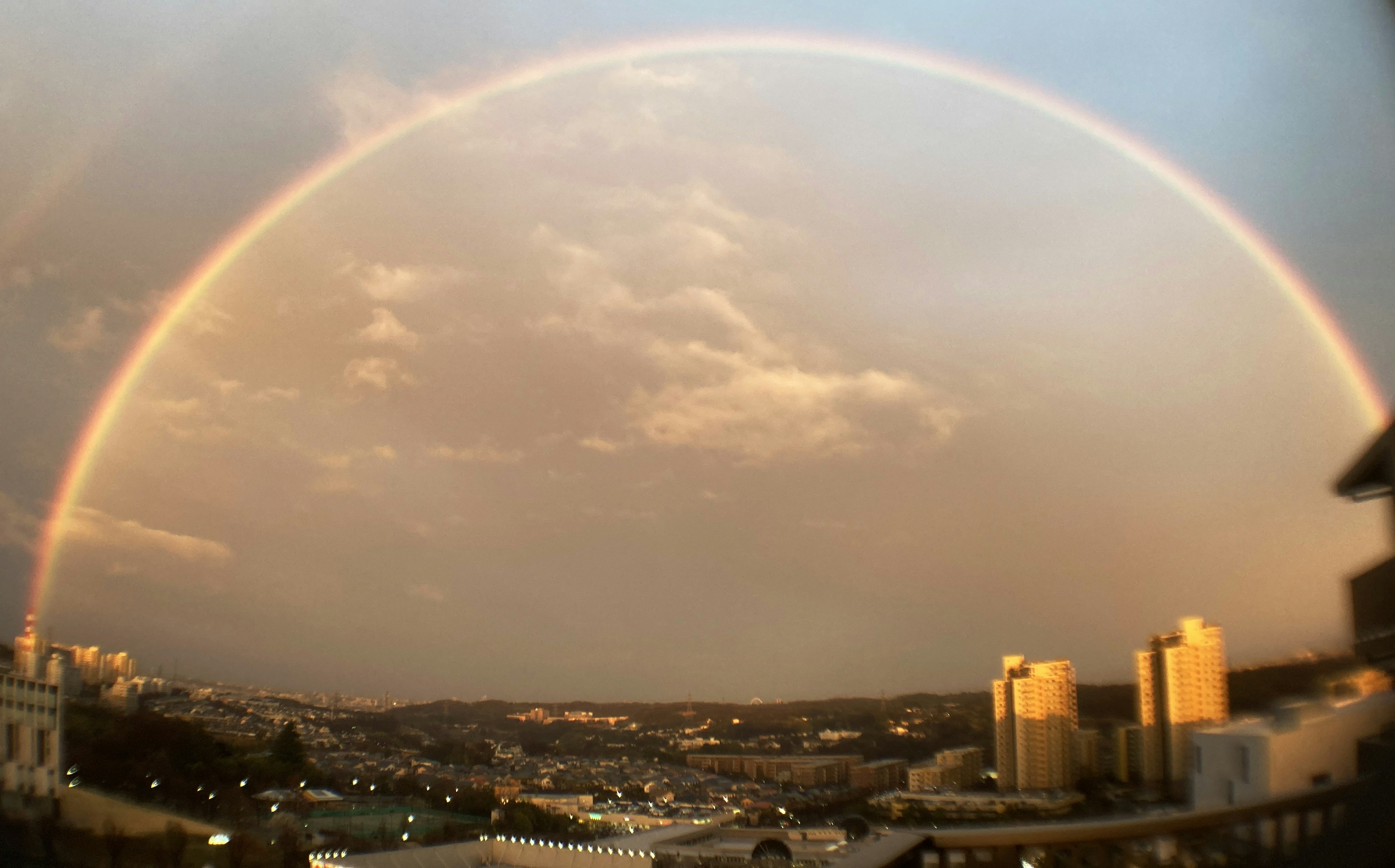 Un arcobaleno vibrante sopra uno skyline cittadino con nuvole