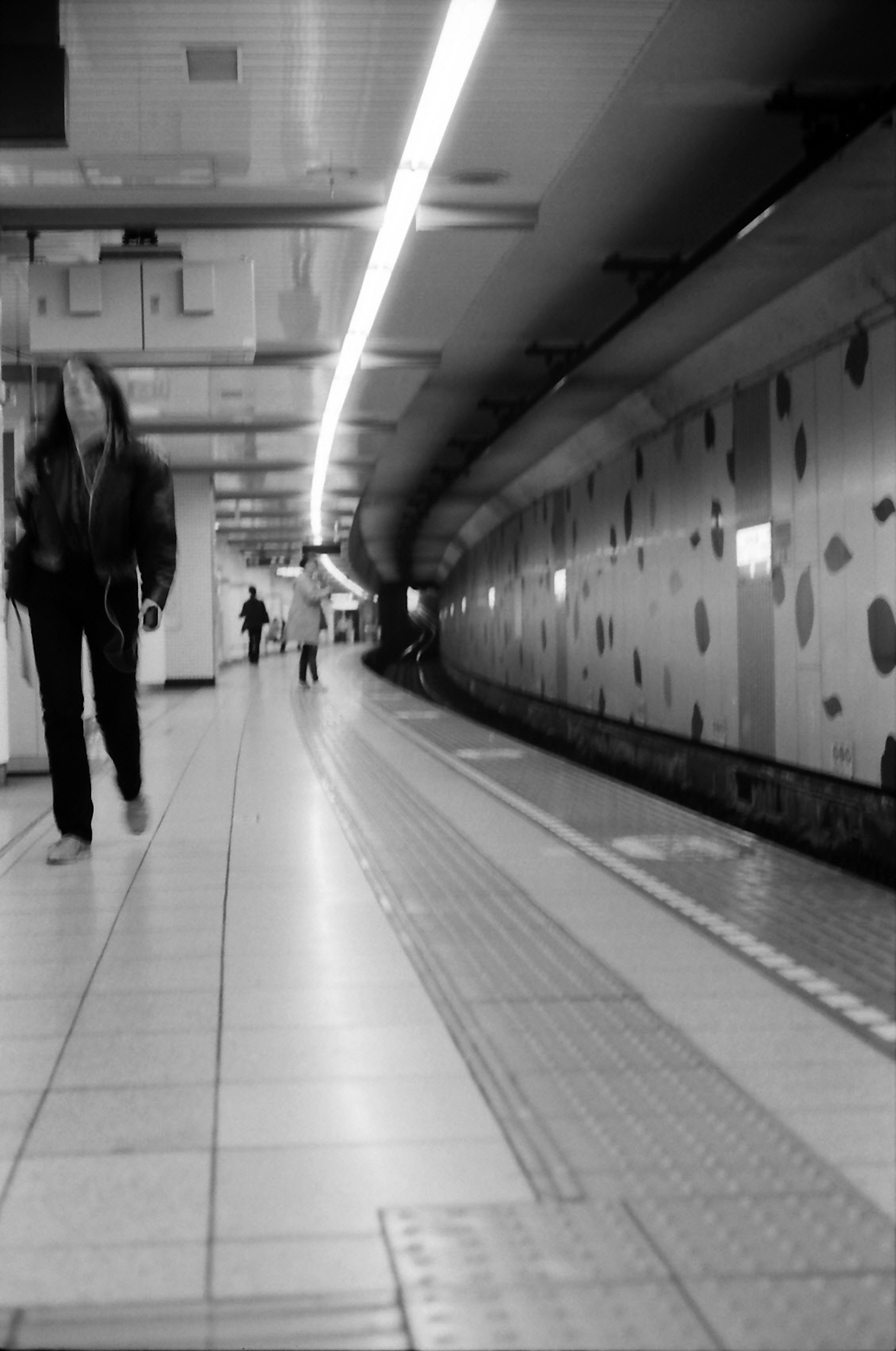 Schwarz-Weiß-U-Bahn-Station mit gehenden Personen und gepunkteter Wand