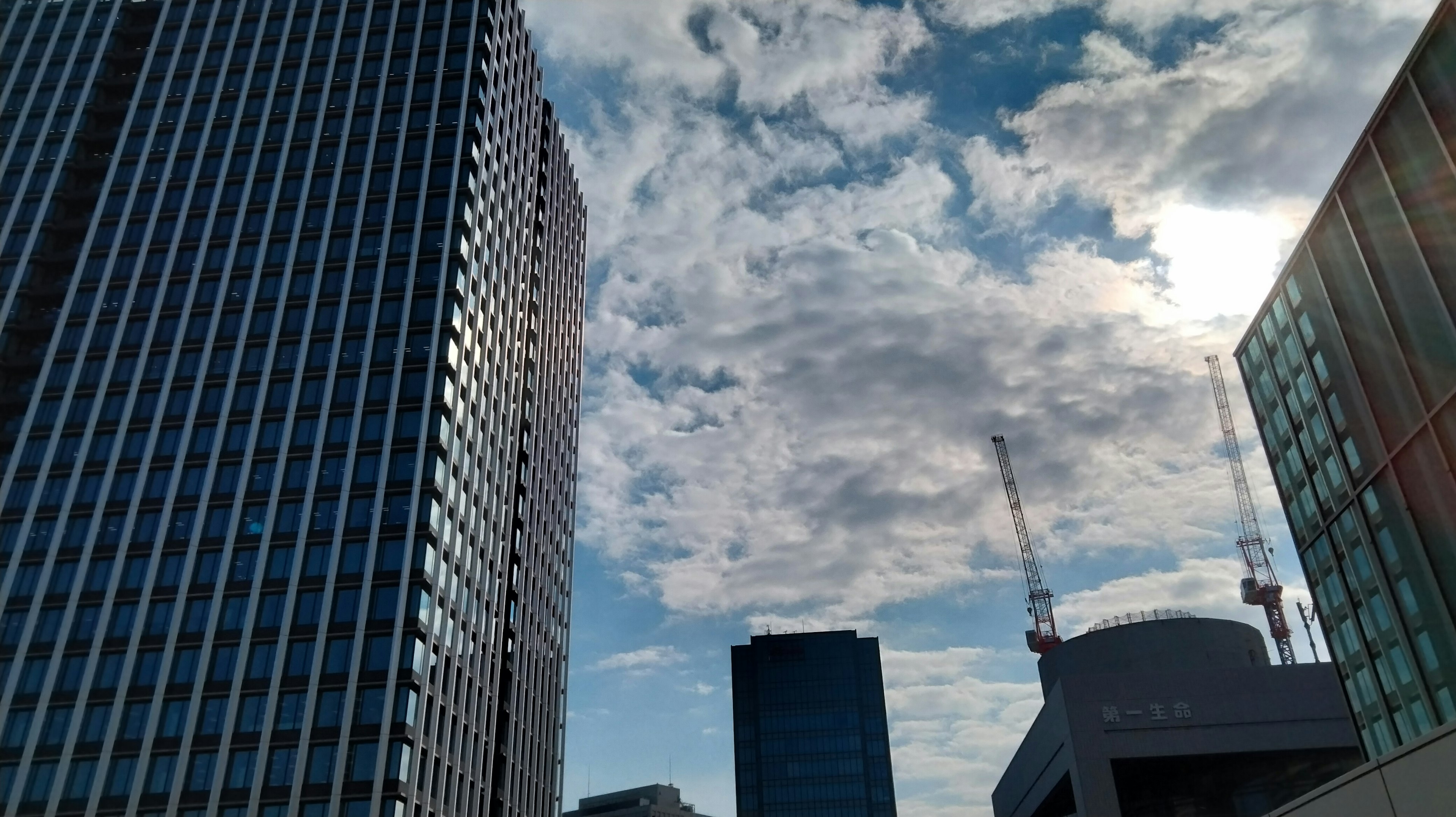 Urban skyline with tall buildings under a blue sky and clouds