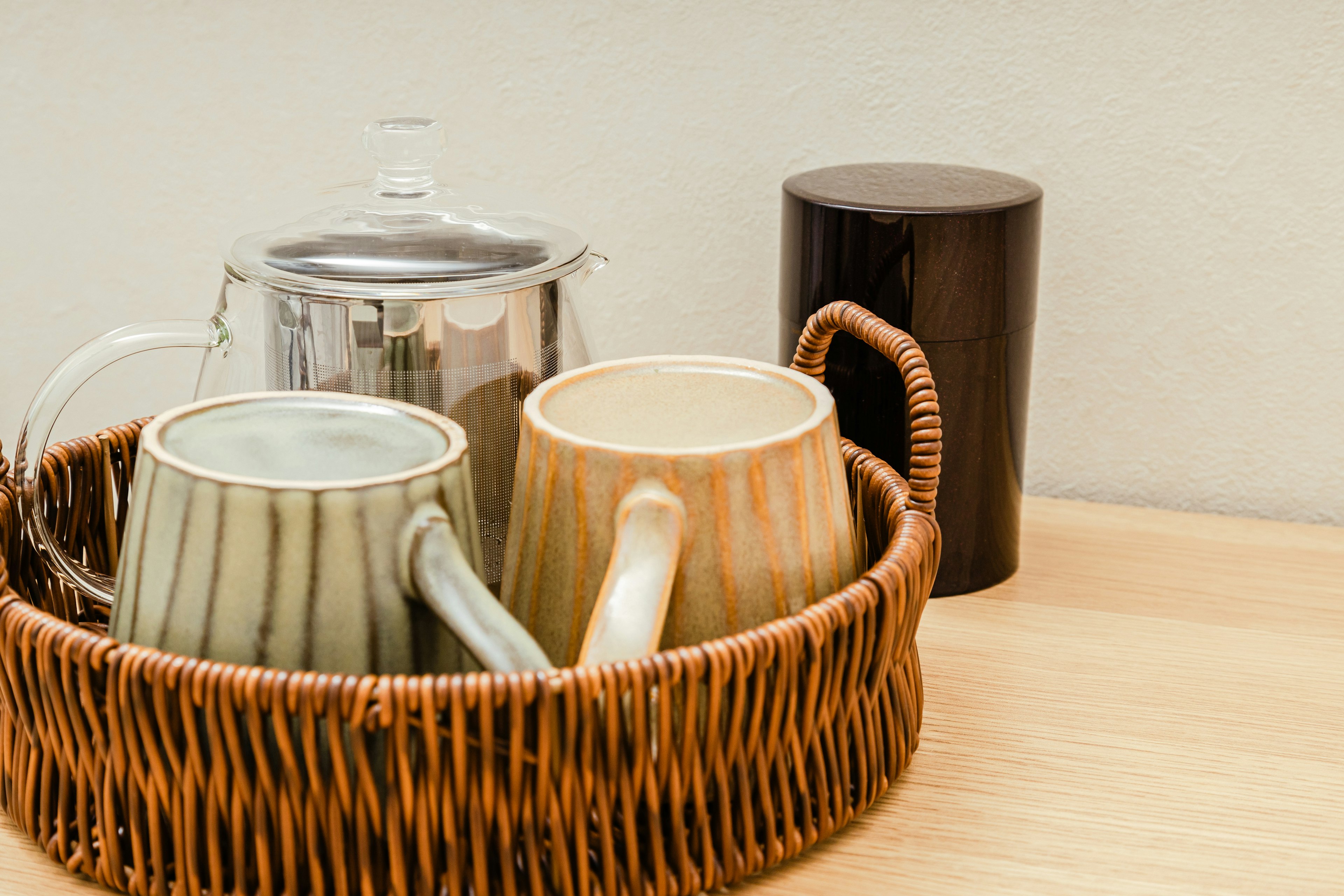 Deux mugs colorés et une théière dans un panier en osier