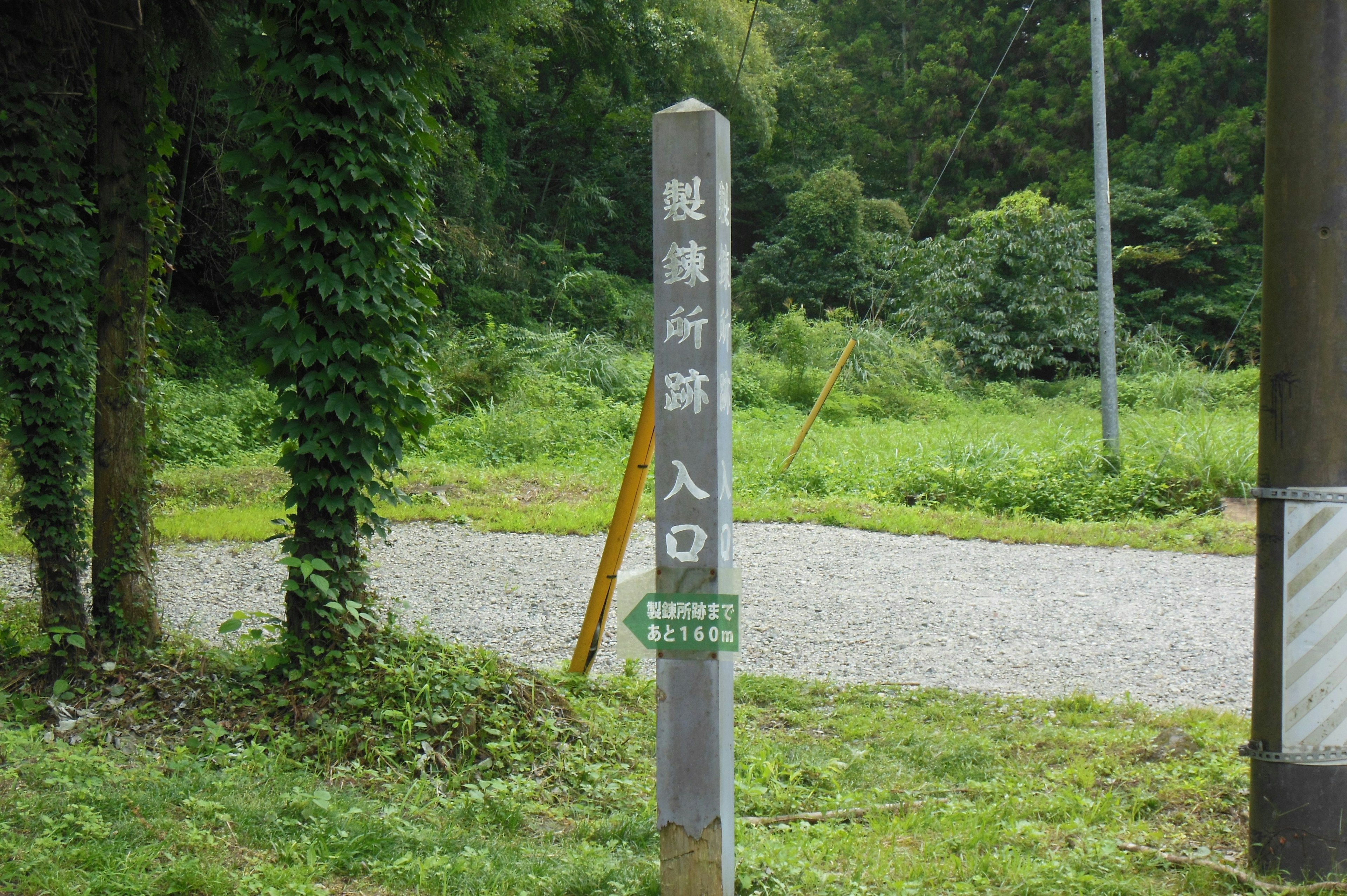 Ein Schild, das den Eingang umgeben von Grün markiert