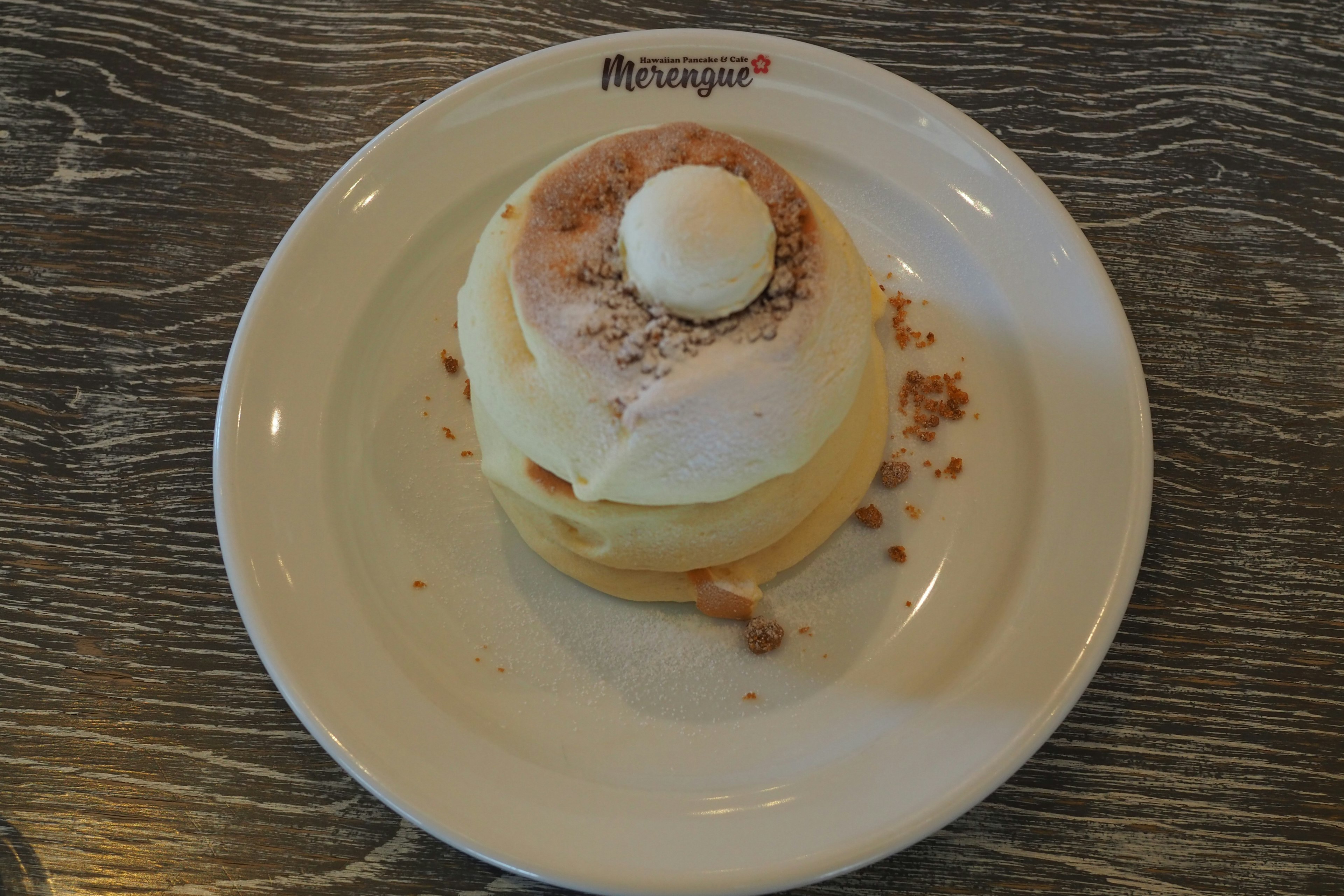 Fluffy pancakes topped with ice cream and cinnamon powder on a white plate