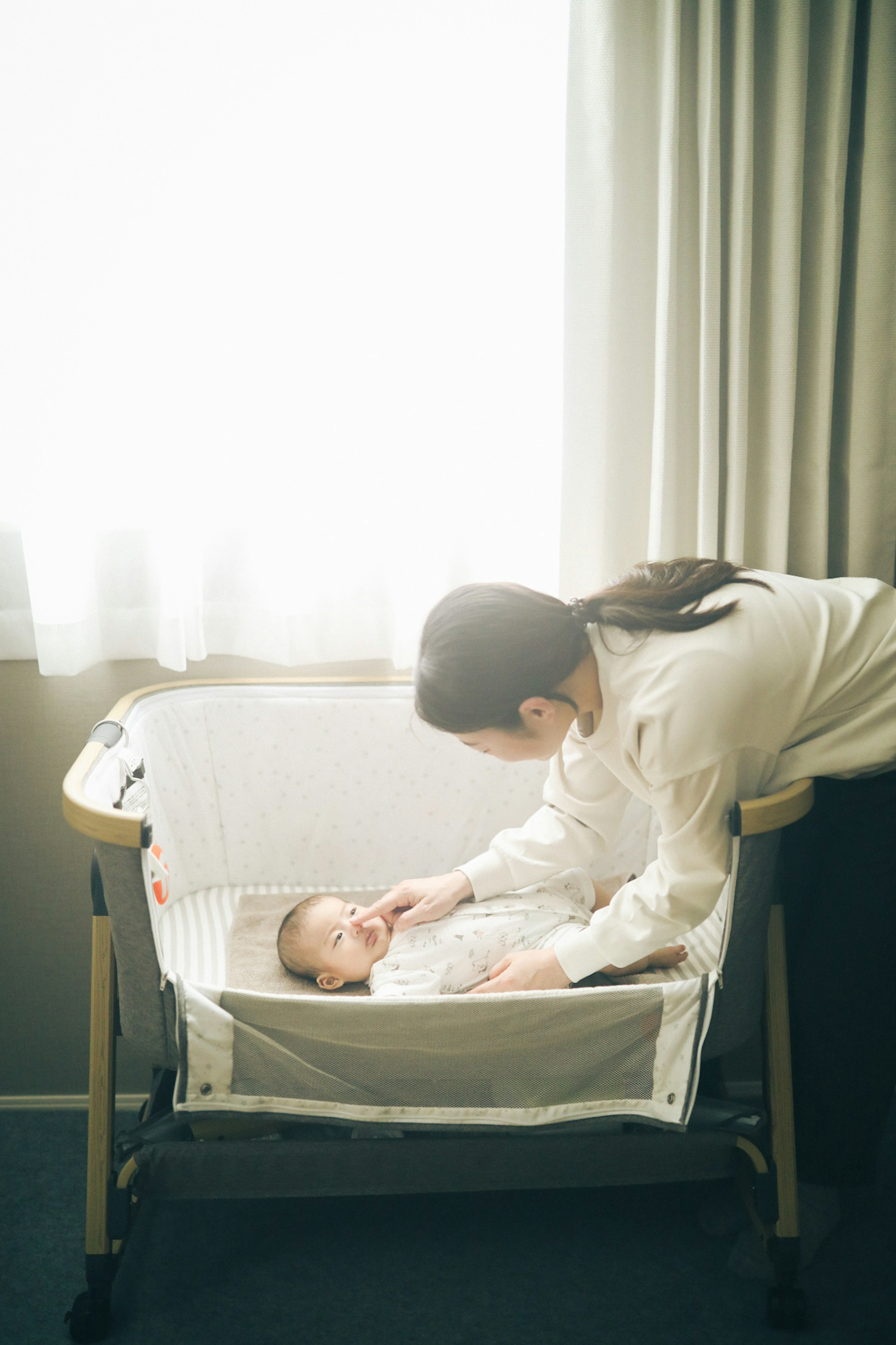 Momento tenero di una madre che veglia sul suo bambino Luce morbida dalla finestra illumina la stanza