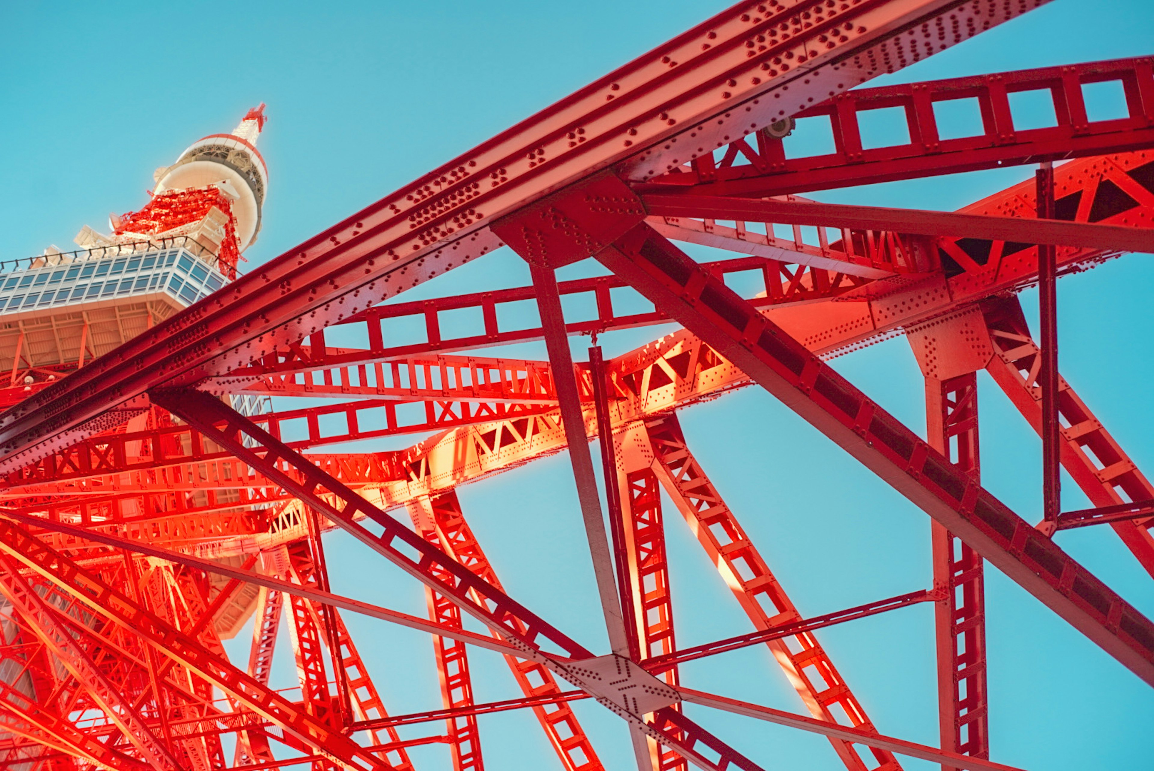 Close-up of Tokyo Tower's red steel structure against a blue sky