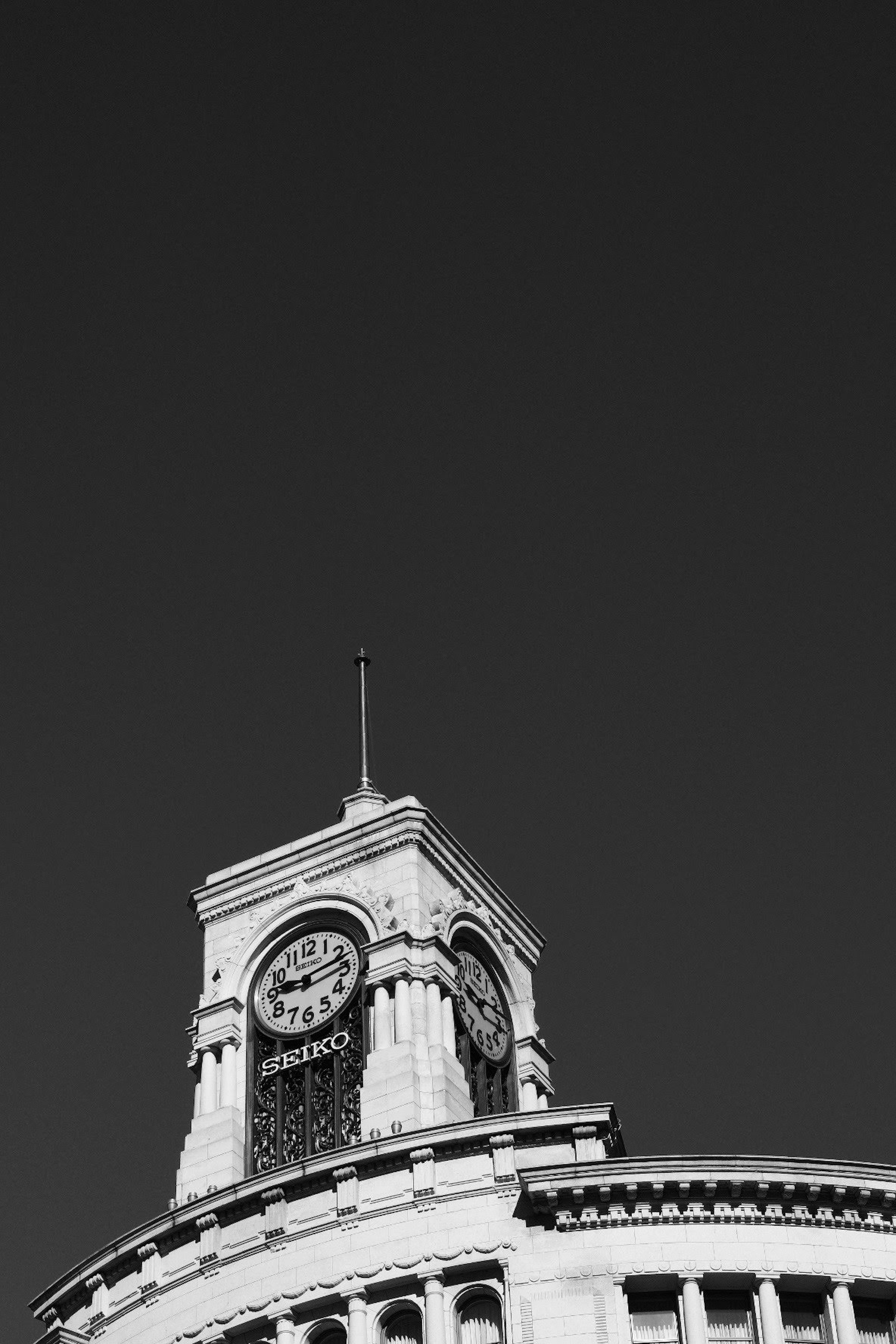 Black and white image of the upper part of a clock tower building