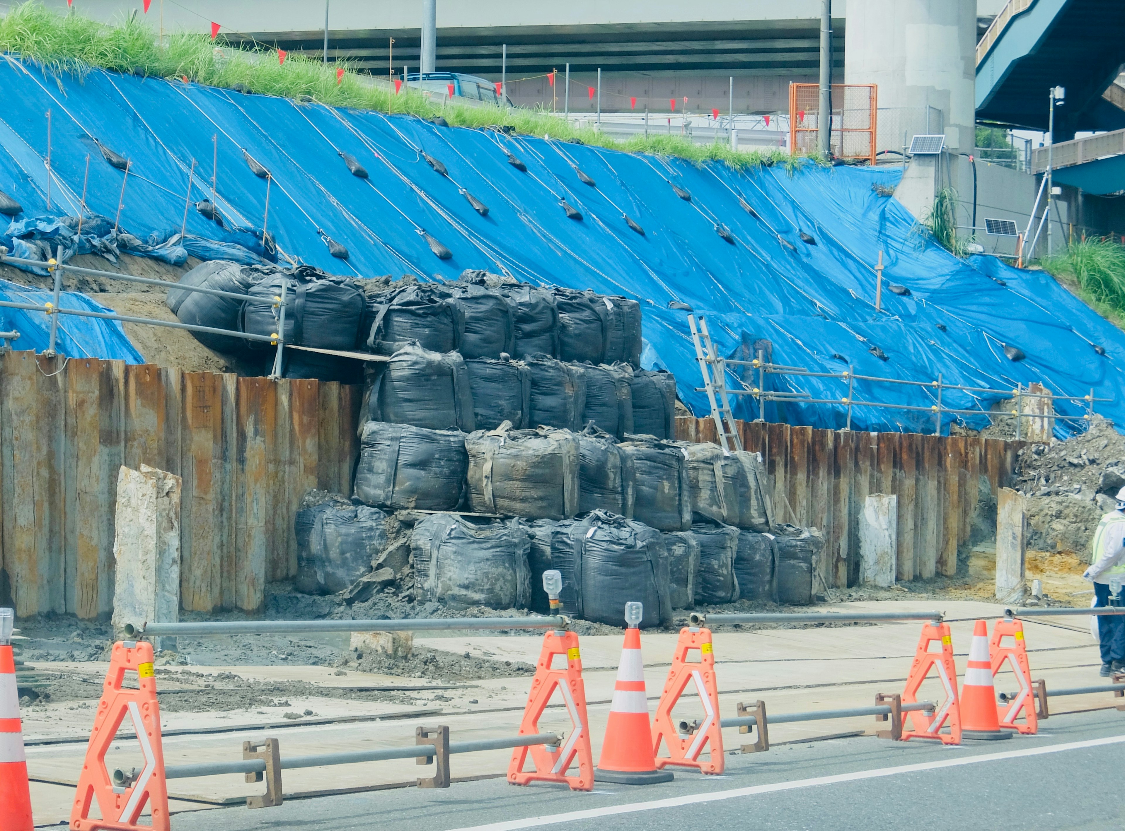 Lokasi konstruksi dengan dinding penahan dan terpal biru