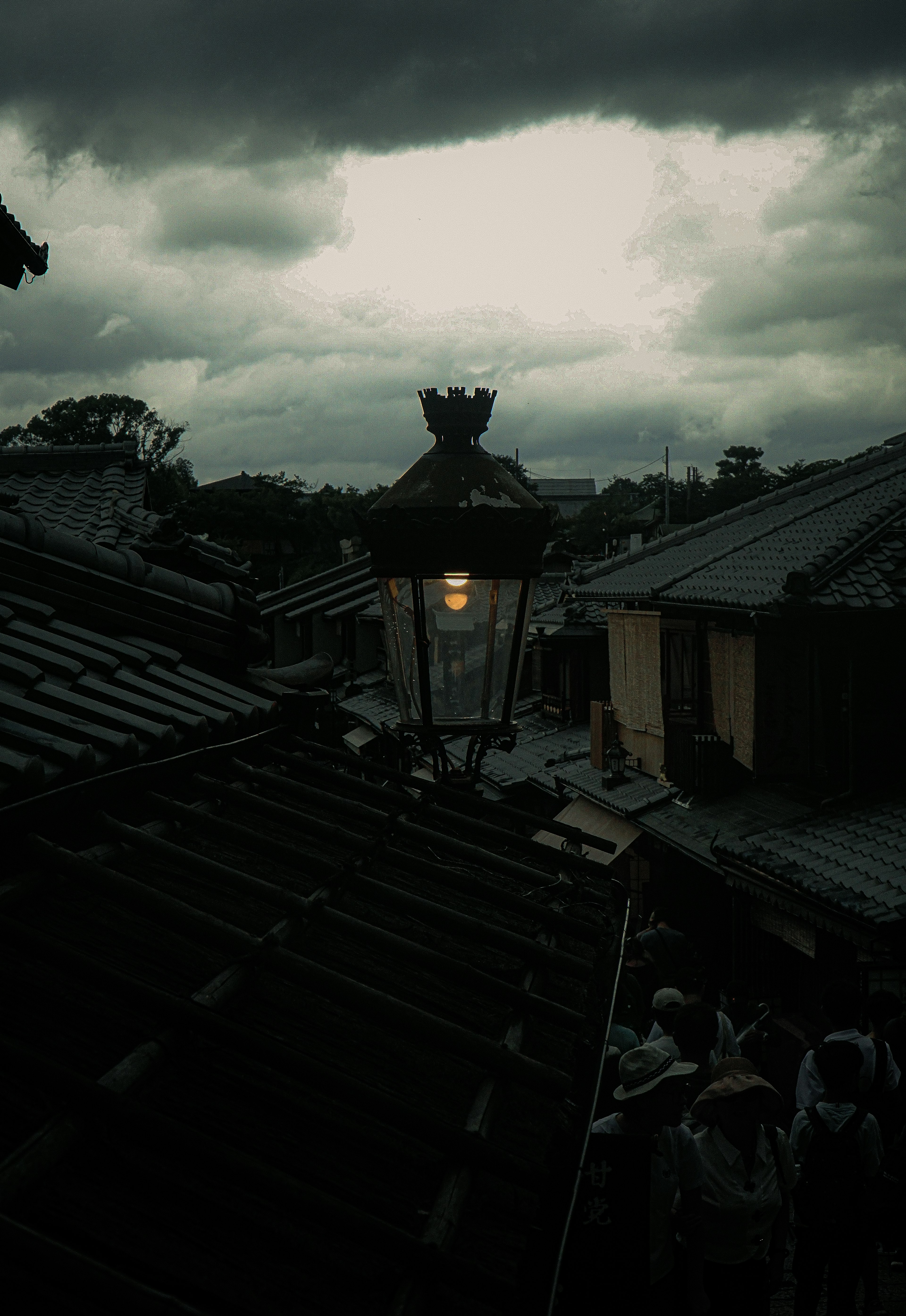 Eine Straßenlampe unter dunklen Wolken mit Dächern