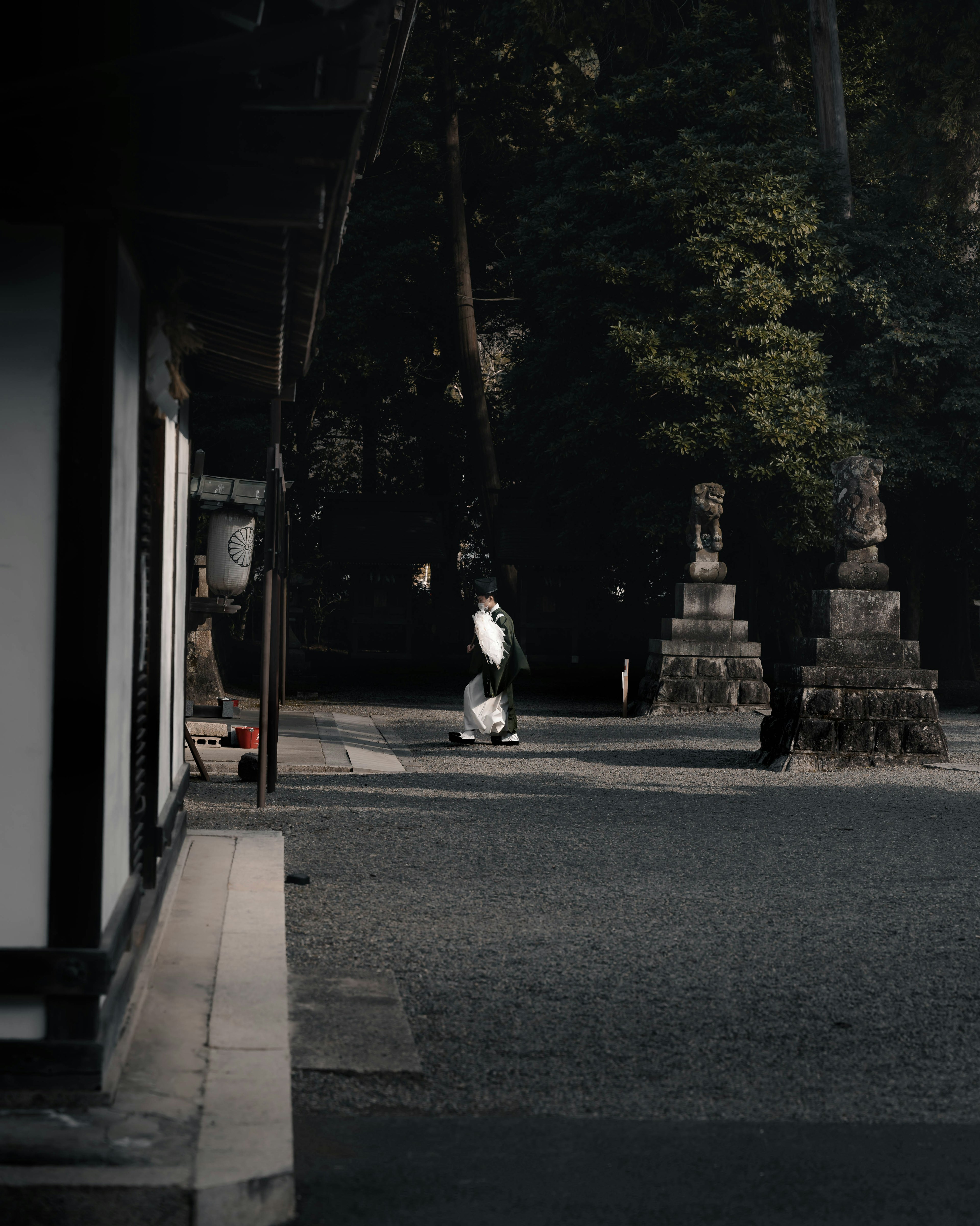 A person walking in a quiet temple courtyard with ancient stone lanterns